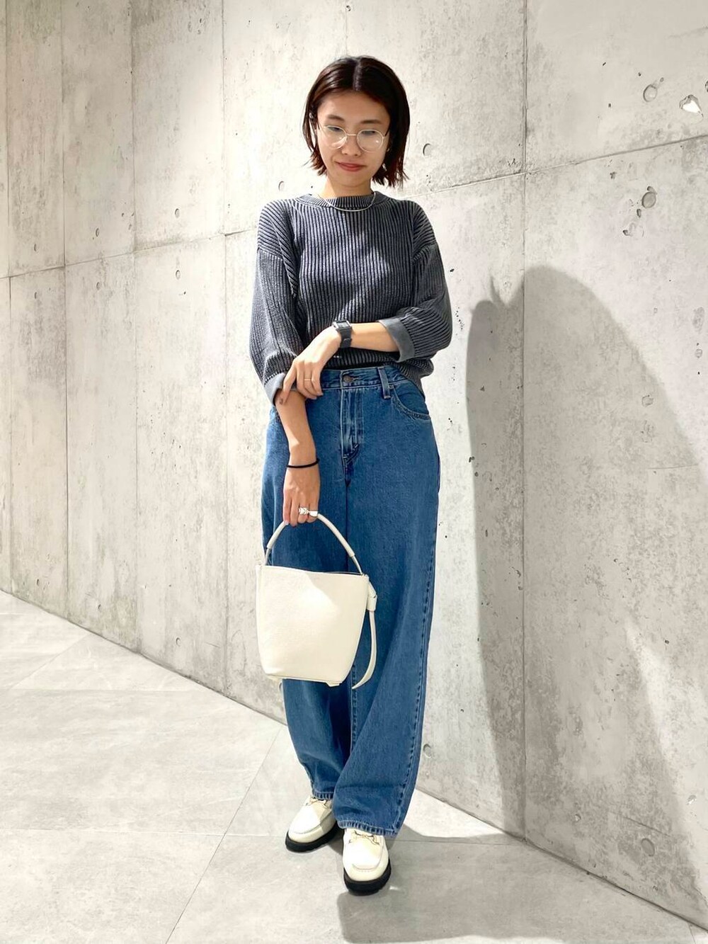 ベージュ系のショルダーバッグ、ホワイト系のローファー、ブラック系のニット/セーターを着用したレディースの夏コーディネートの2枚目の写真