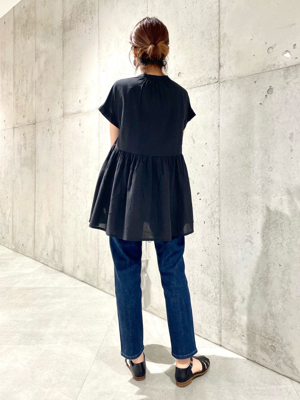 ブラック系のサンダル、ブルー系のデニムパンツ、ホワイト系のショルダーバッグを着用したレディースの夏コーディネートの3枚目の写真