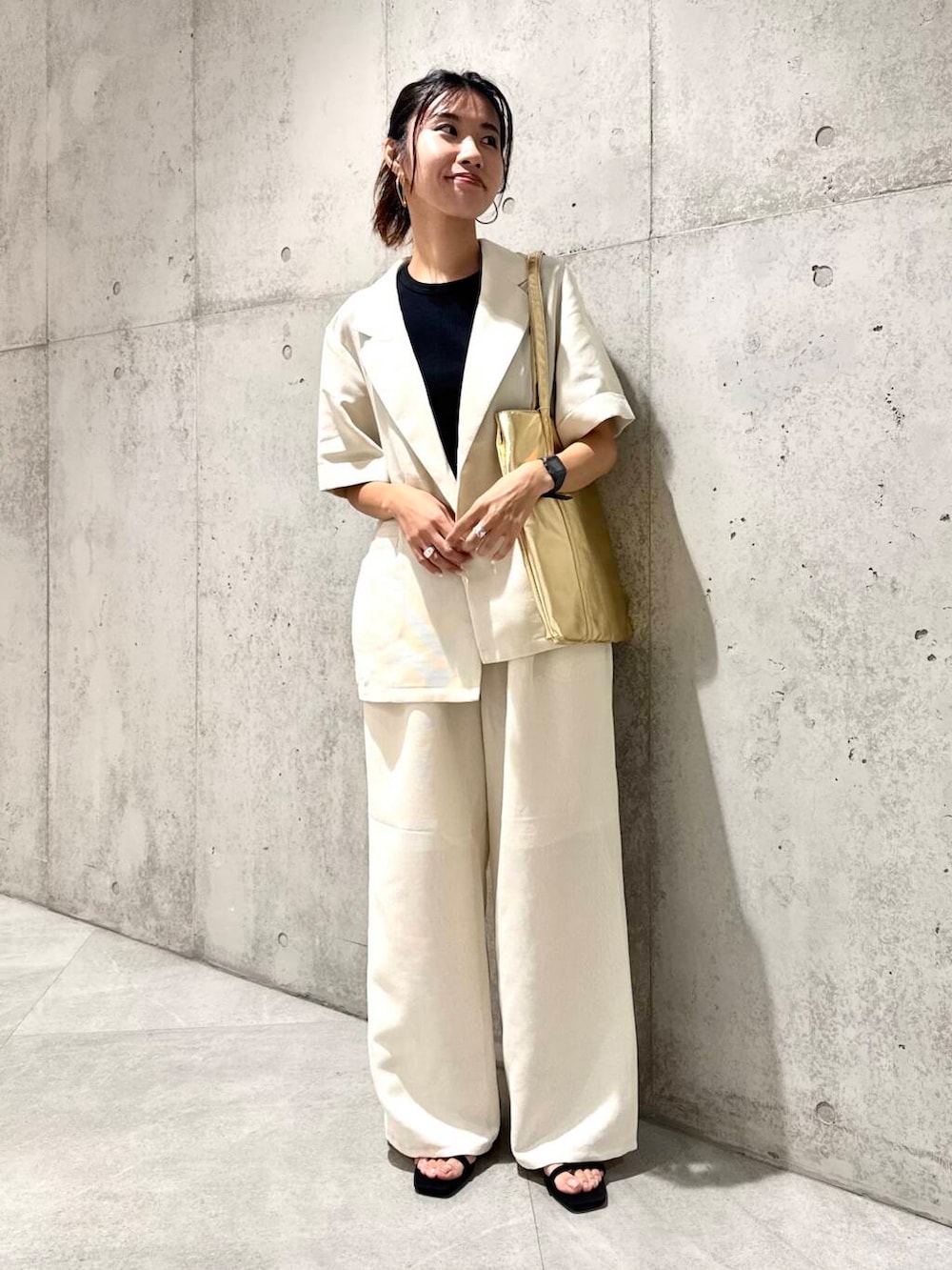 ゴールド系のトートバッグ、ブラック系のサンダル、ホワイト系のその他パンツを着用したレディースの夏コーディネートの3枚目の写真