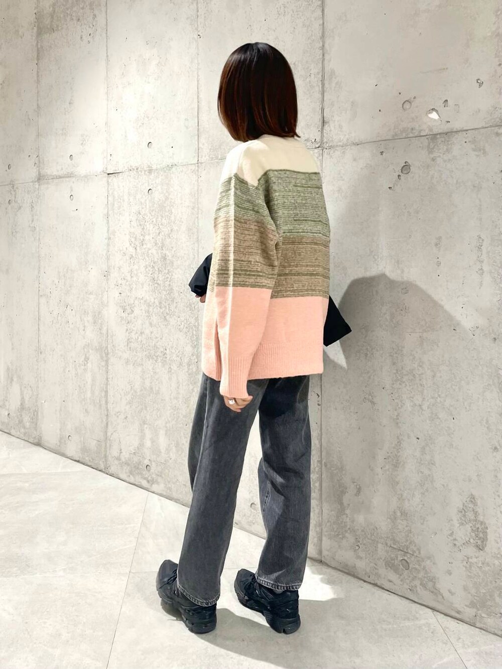 ブラック系のデニムパンツ、ブラック系のダウンジャケット/コート、ピンク系のニット/セーターを着用したレディースの秋コーディネートの6枚目の写真