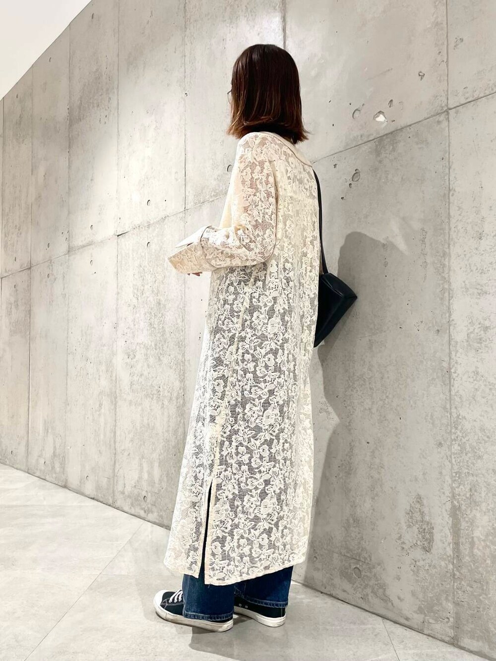 ブルー系のデニムパンツ、ブラック系のショルダーバッグ、ホワイト系のワンピースを着用したレディースの秋コーディネートの4枚目の写真