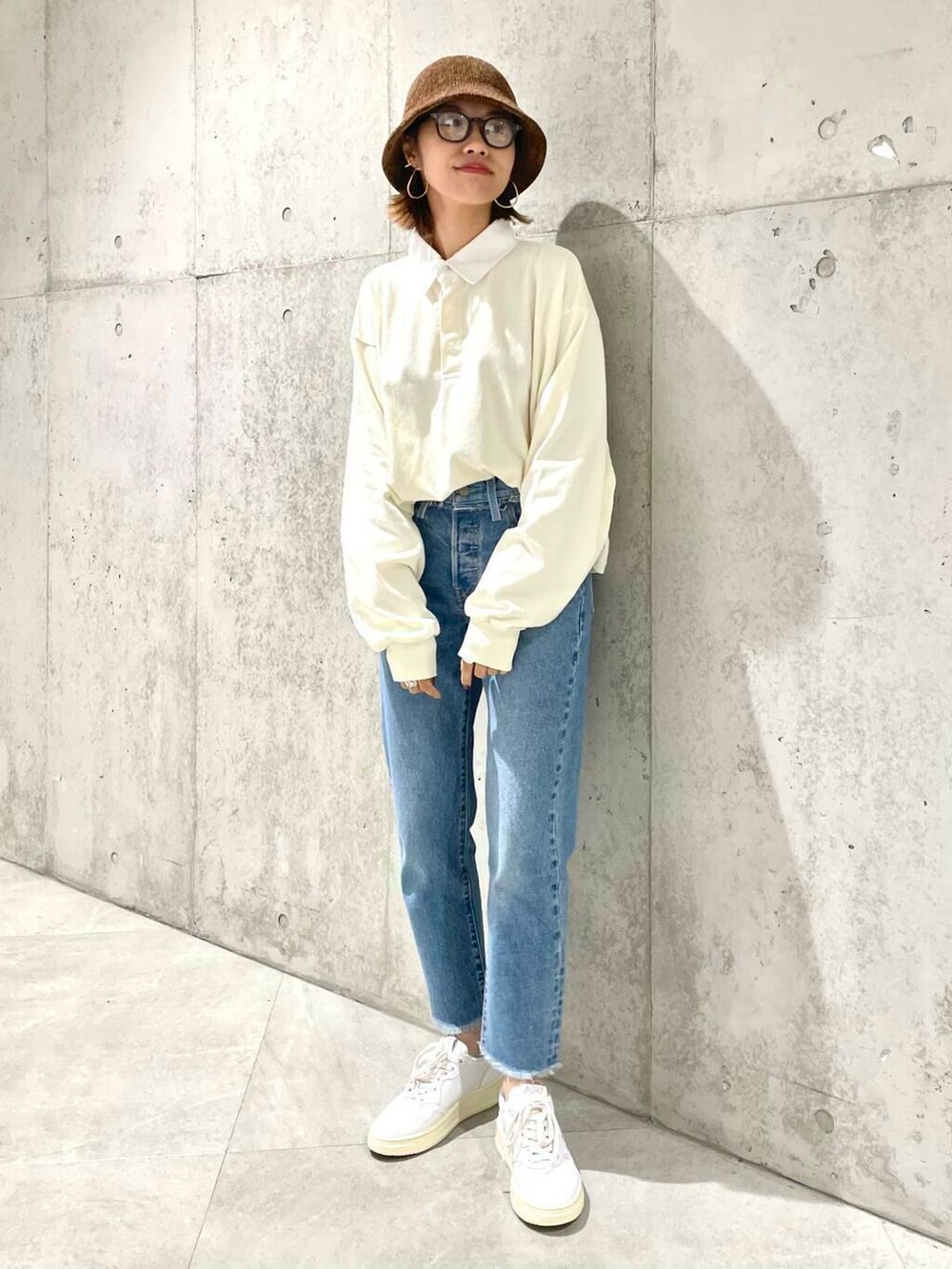 ベージュ系のポロシャツ、ブルー系のデニムパンツ、ホワイト系のスニーカーを着用したレディースの夏コーディネートの3枚目の写真