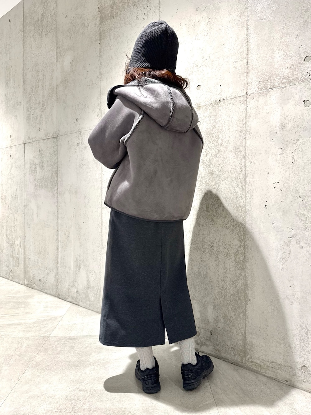 ブラック系のムートンコート、グレー系のニット/セーター、グレー系のスカートを着用したレディースの冬コーディネートの4枚目の写真