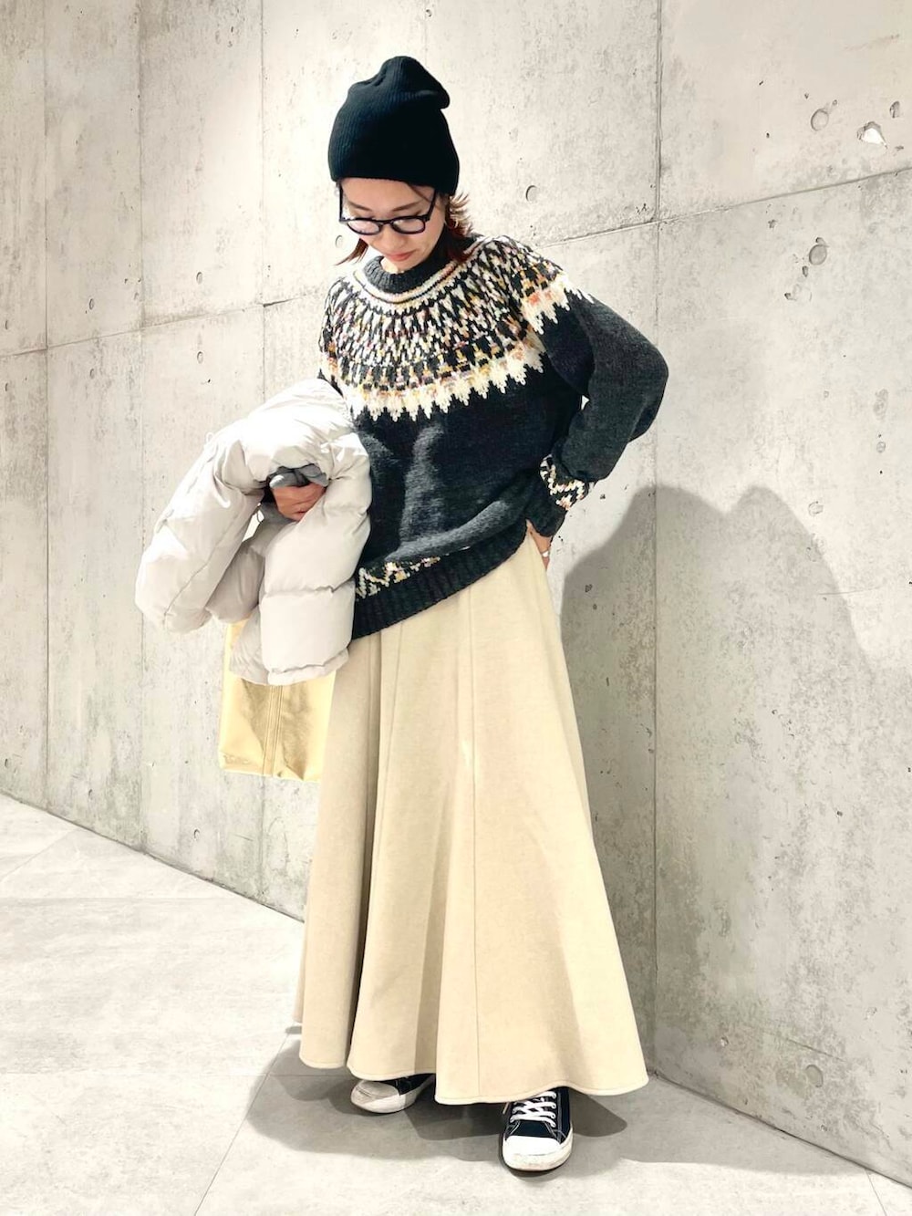 ホワイト系のダウンジャケット/コート、ベージュ系のスカート、グレー系のニット/セーターを着用したレディースの冬コーディネートの4枚目の写真