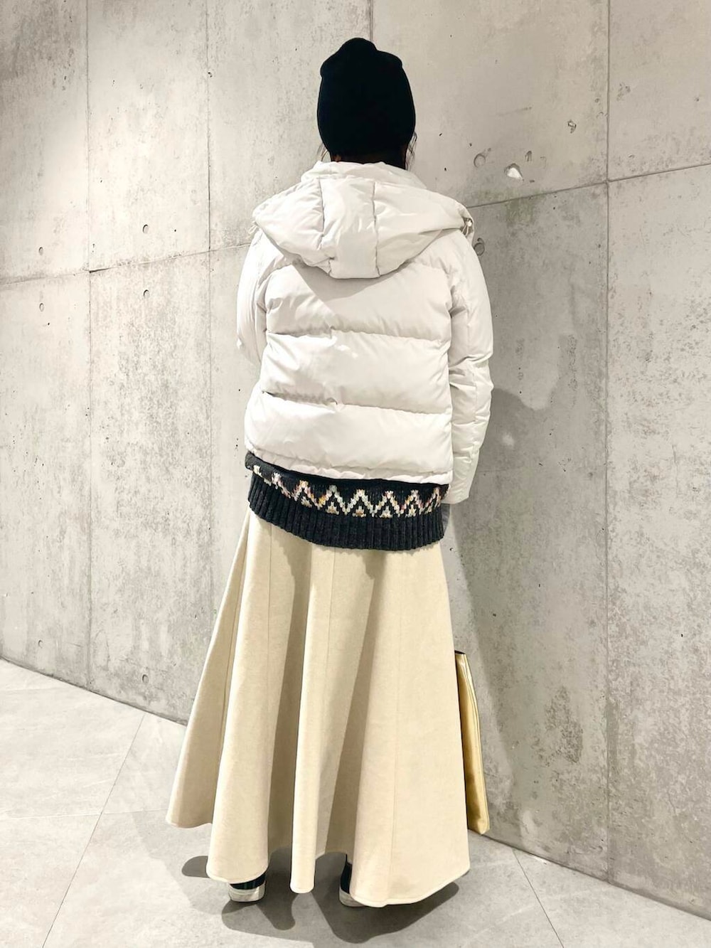 ホワイト系のダウンジャケット/コート、ベージュ系のスカート、グレー系のニット/セーターを着用したレディースの冬コーディネートの3枚目の写真