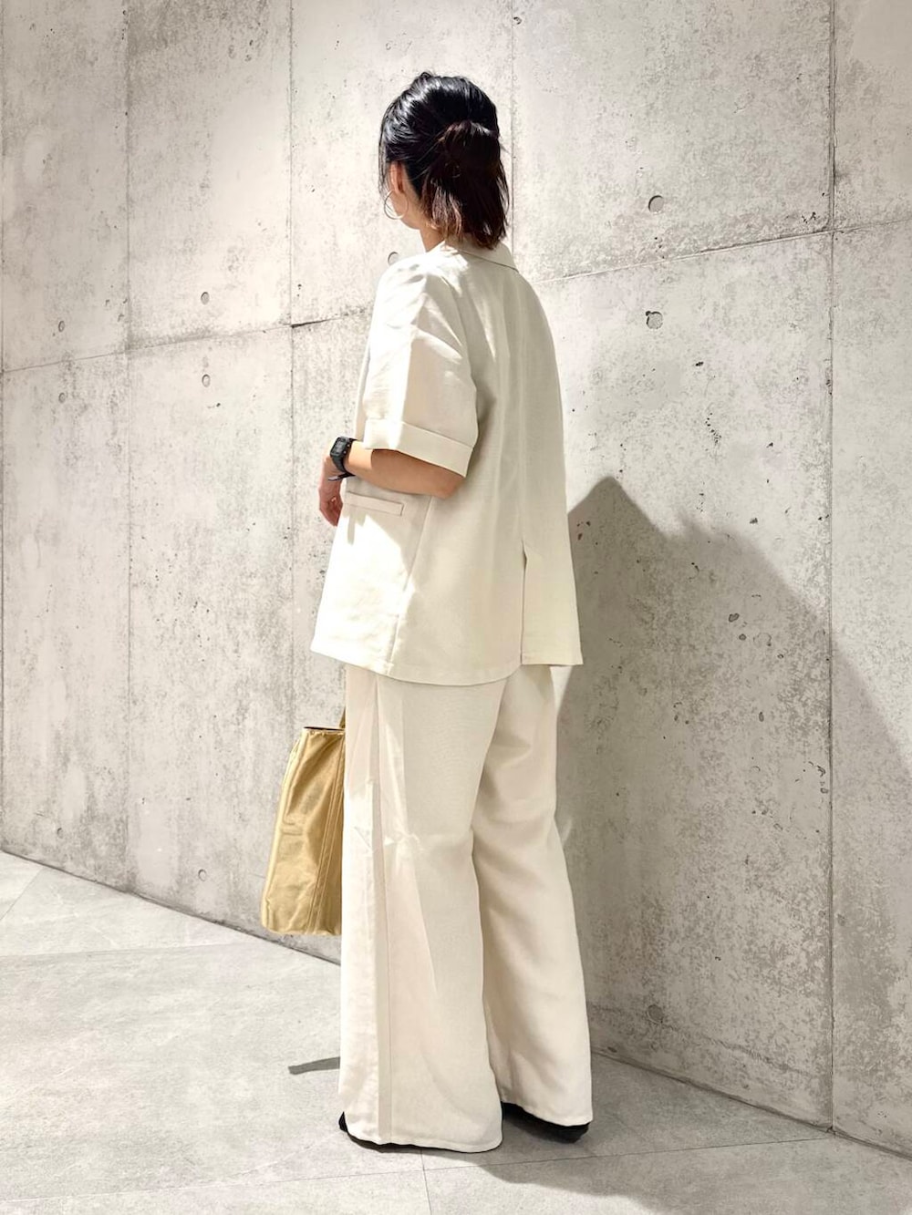 ゴールド系のトートバッグ、ブラック系のサンダル、ホワイト系のその他パンツを着用したレディースの夏コーディネートの4枚目の写真