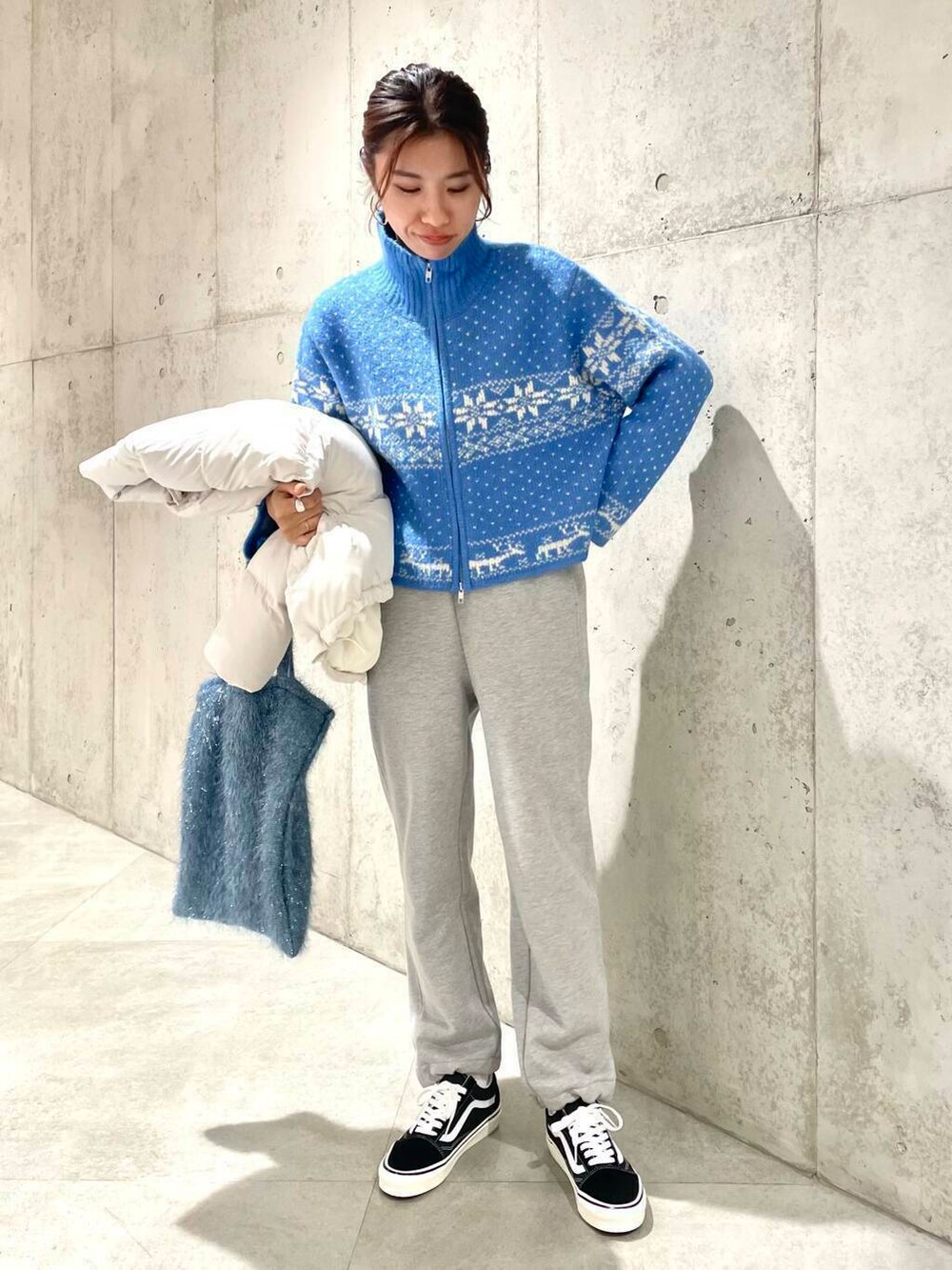 ブラック系のスニーカー、ブルー系のニット/セーター、ブルー系のトートバッグを着用したレディースの冬コーディネートの6枚目の写真