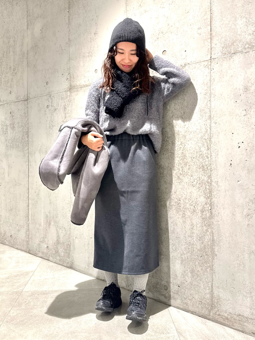 ブラック系のムートンコート、グレー系のニット/セーター、グレー系のスカートを着用したレディースの冬コーディネートの5枚目の写真