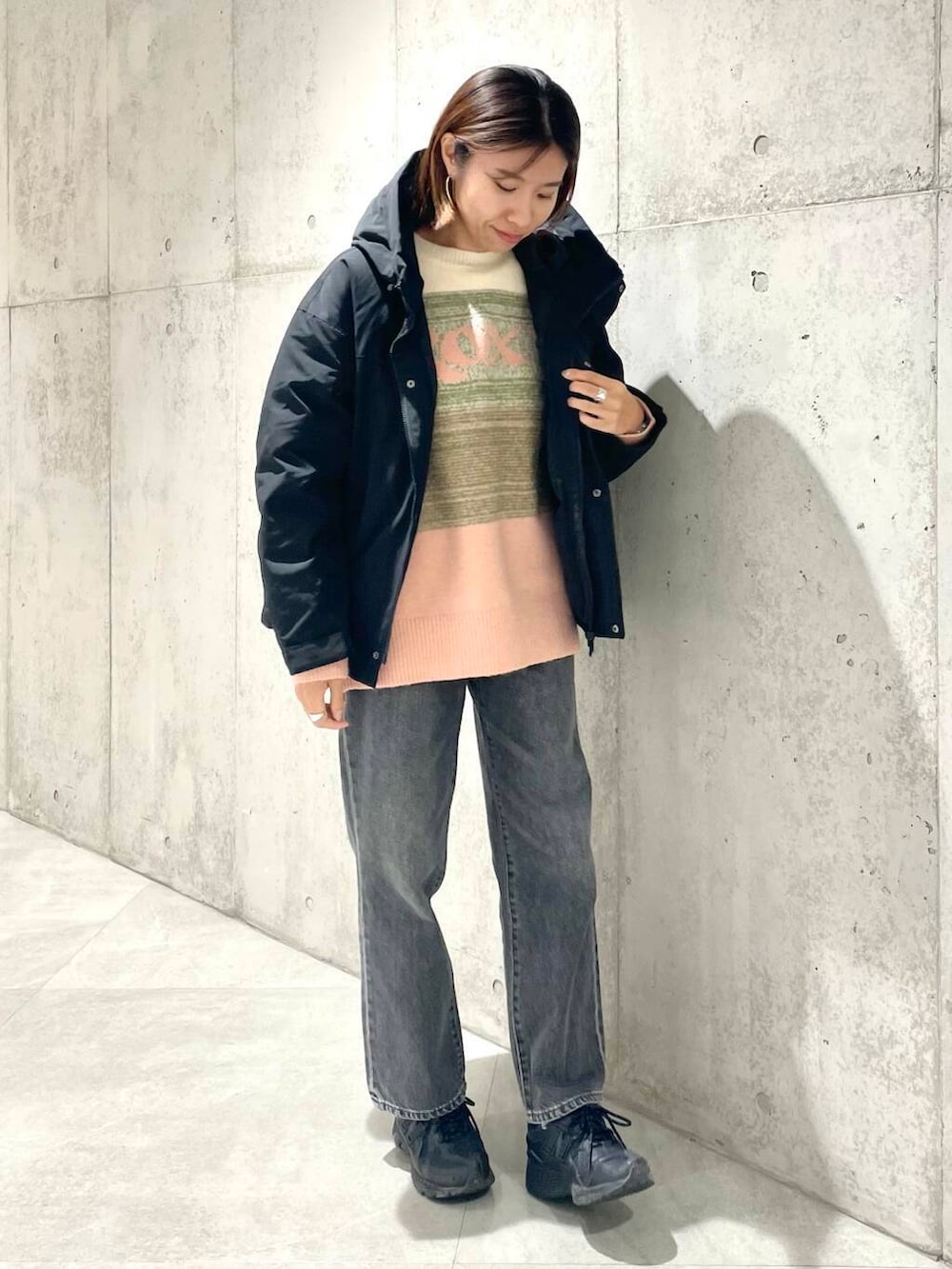 ブラック系のデニムパンツ、ブラック系のダウンジャケット/コート、ピンク系のニット/セーターを着用したレディースの秋コーディネートの2枚目の写真