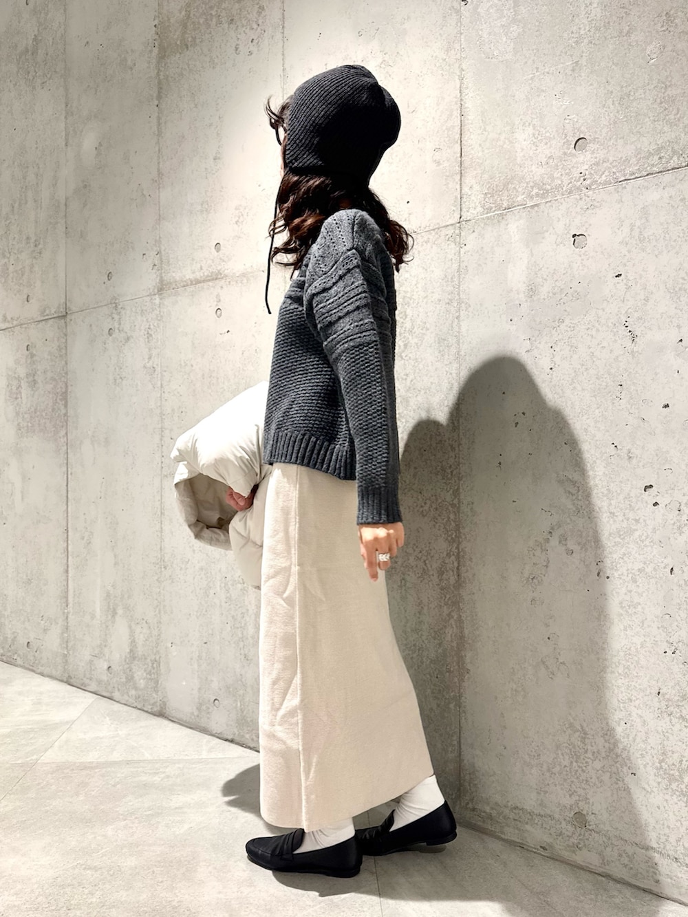 ホワイト系のスカート、グリーン系のニット/セーター、ホワイト系のダウンジャケット/コートを着用したレディースの秋コーディネートの6枚目の写真