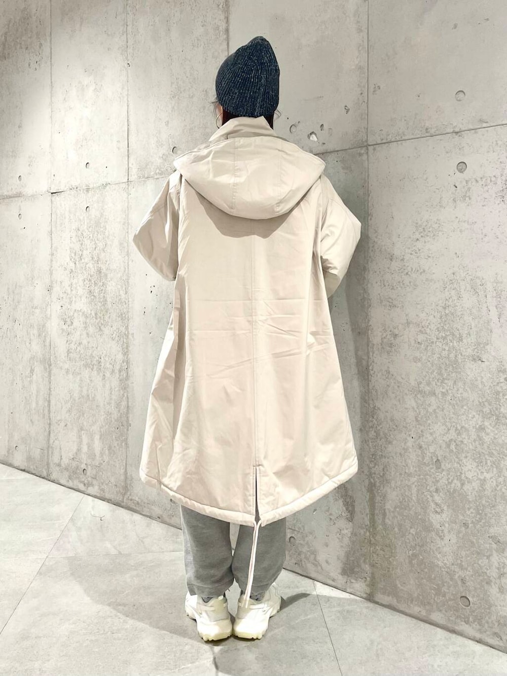 ホワイト系のスニーカー、ベージュ系のダウンジャケット/コート、ブルー系のニット/セーターを着用したレディースの冬コーディネートの4枚目の写真