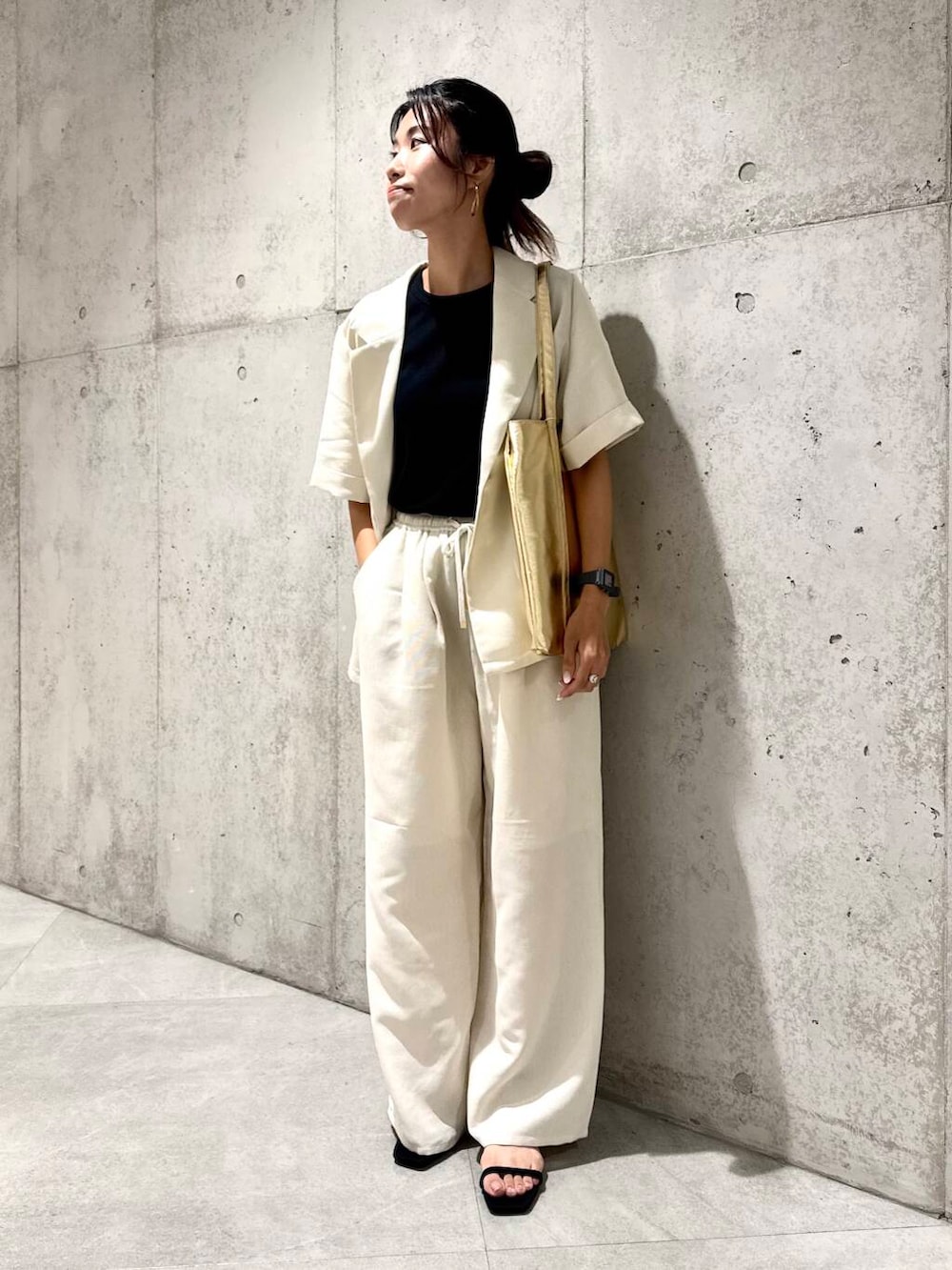 ゴールド系のトートバッグ、ブラック系のサンダル、ホワイト系のその他パンツを着用したレディースの夏コーディネートの2枚目の写真