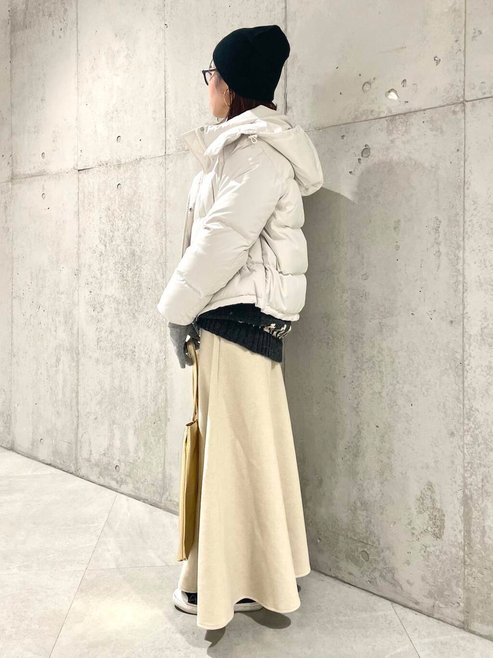 ホワイト系のダウンジャケット/コート、ベージュ系のスカート、グレー系のニット/セーターを着用したレディースの冬コーディネートの2枚目の写真