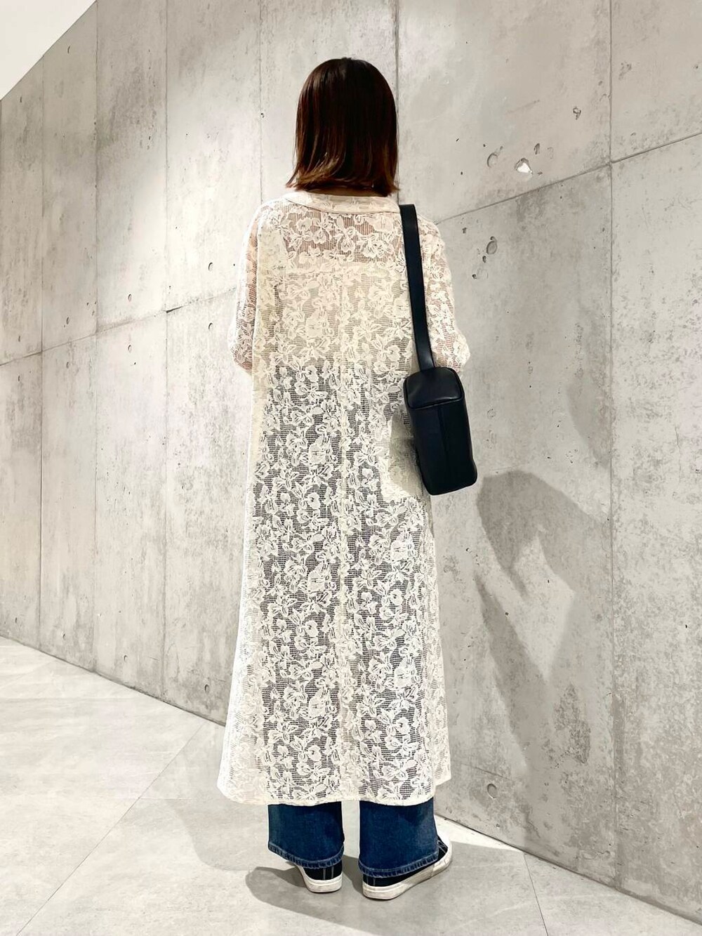 ブルー系のデニムパンツ、ブラック系のショルダーバッグ、ホワイト系のワンピースを着用したレディースの秋コーディネートの5枚目の写真