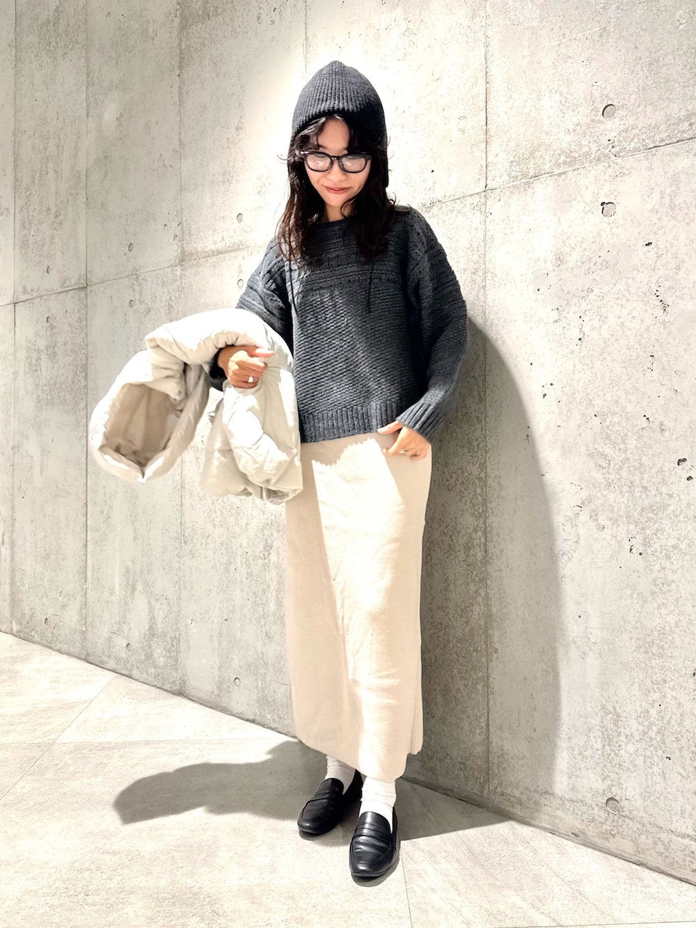ホワイト系のスカート、グリーン系のニット/セーター、ホワイト系のダウンジャケット/コートを着用したレディースの秋コーディネートの5枚目の写真