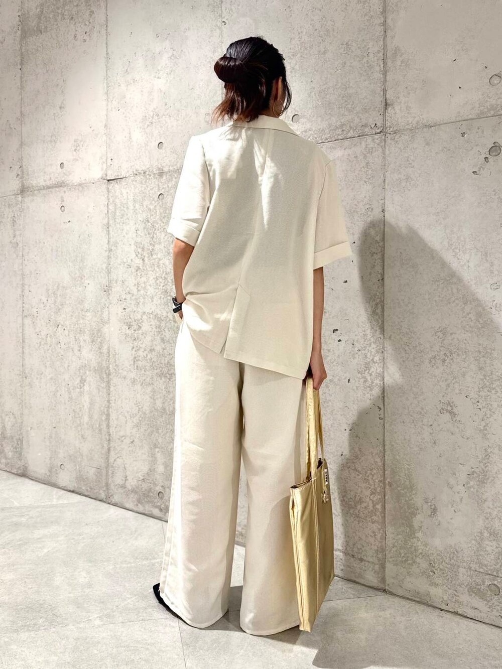 ゴールド系のトートバッグ、ブラック系のサンダル、ホワイト系のその他パンツを着用したレディースの夏コーディネートの5枚目の写真