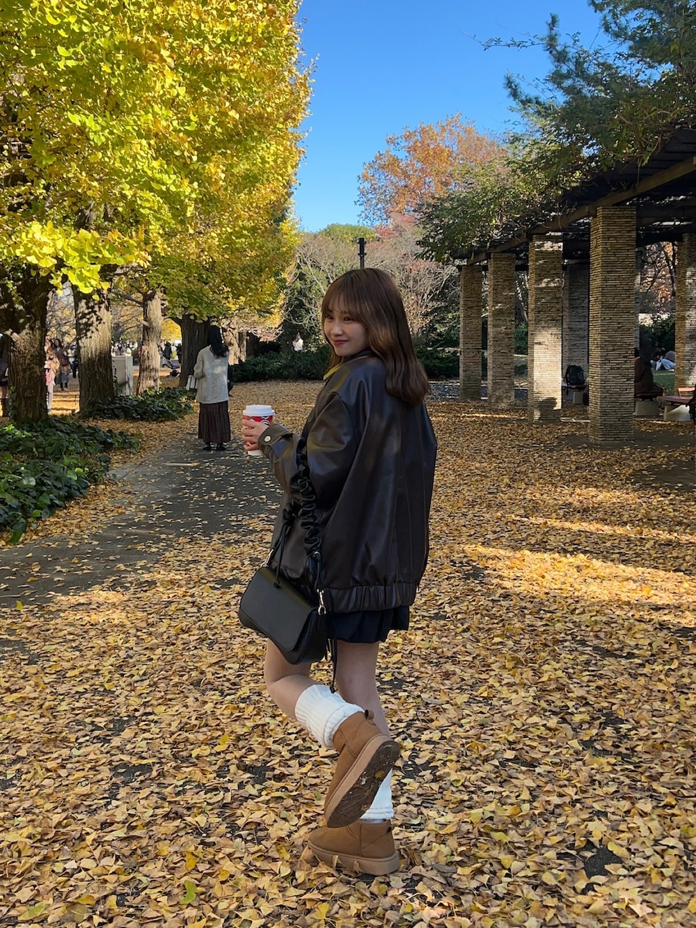 ブラウン系のブルゾン、ベージュ系のブーツ、ホワイト系のニット/セーターを着用したレディースの秋コーディネートの2枚目の写真