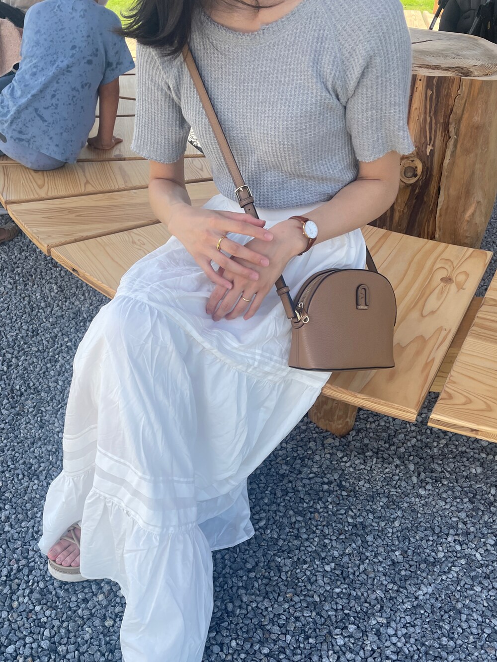 ホワイト系のスカート、ベージュ系のサンダル、グレー系のTシャツ/カットソーを着用したレディースの夏コーディネートの2枚目の写真