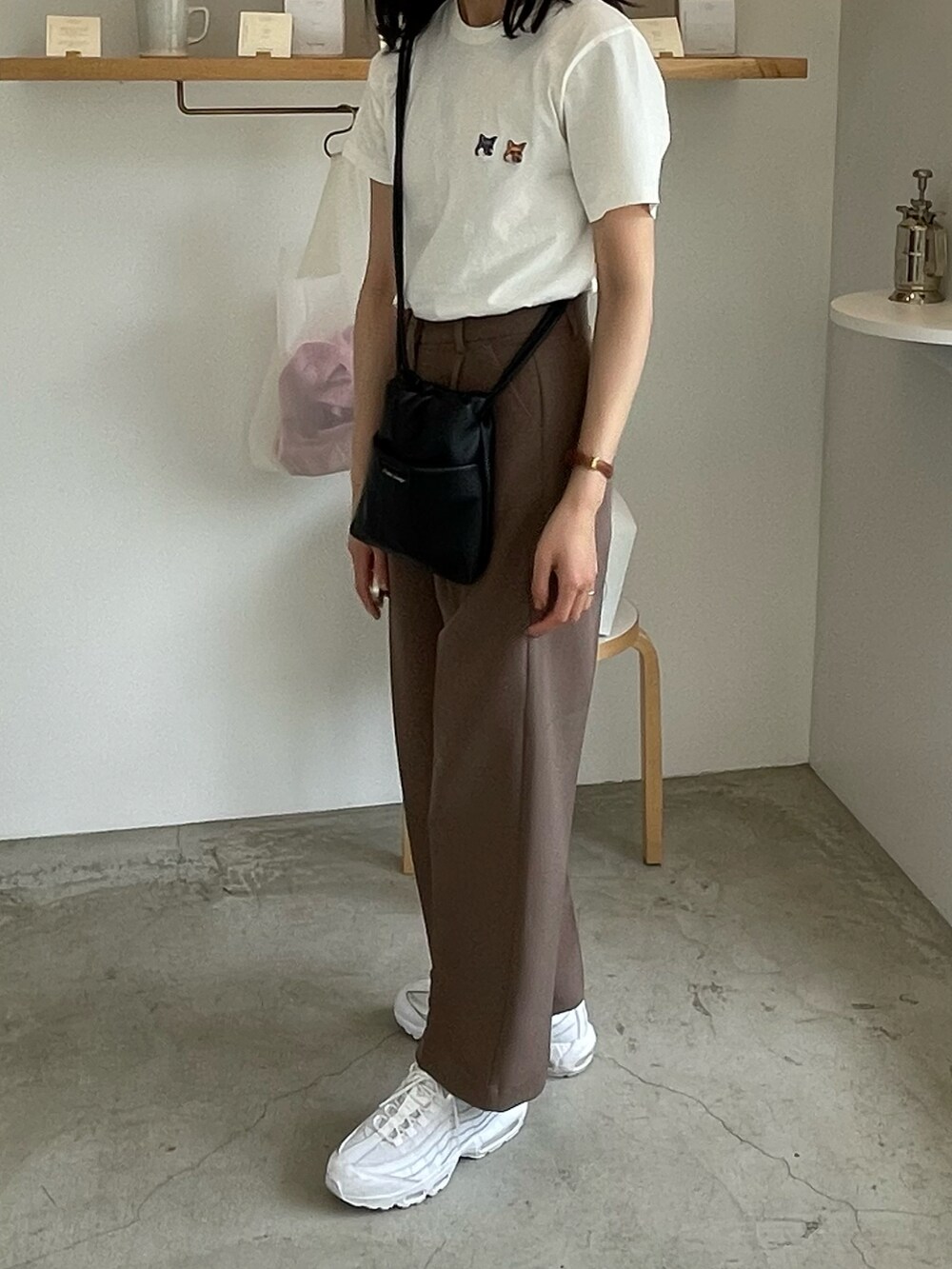 ブラウン系のスラックス、ホワイト系のTシャツ/カットソー、ベージュ系のシャツ/ブラウスを着用したレディースの夏コーディネートの3枚目の写真