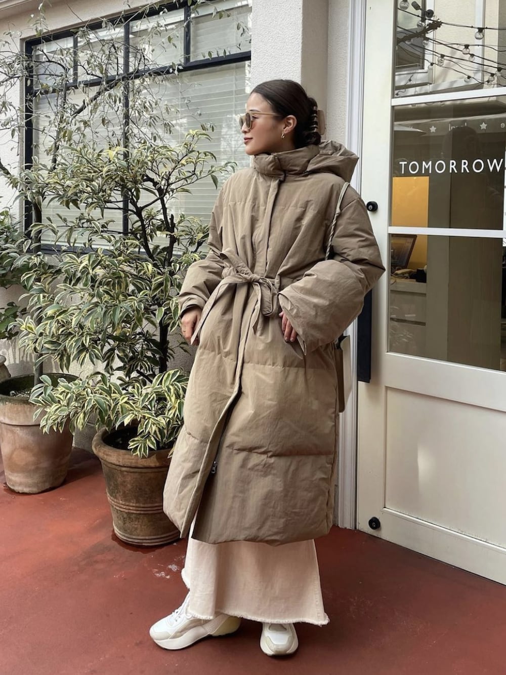 ベージュ系のダウンジャケット/コート、ホワイト系のスカート、ベージュ系のスニーカーを着用したレディースの冬コーディネートの2枚目の写真