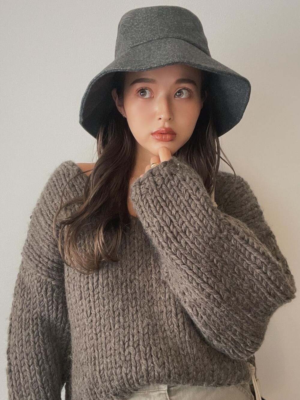 グレー系のニット/セーター、ベージュ系のスカート、グレー系のハットを着用したレディースの秋コーディネートの2枚目の写真