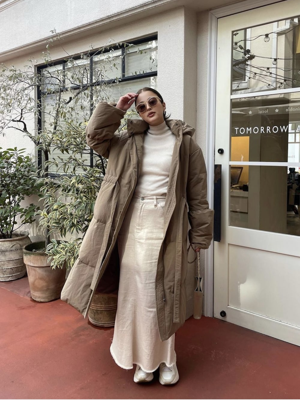 ベージュ系のダウンジャケット/コート、ホワイト系のスカート、ベージュ系のスニーカーを着用したレディースの冬コーディネートの3枚目の写真