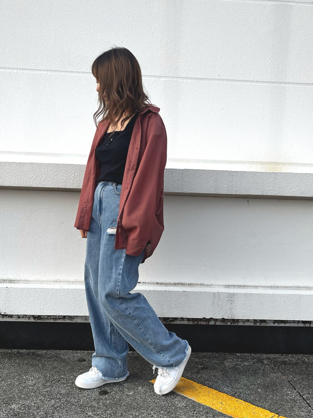 ブルー系のデニムパンツ、ホワイト系のスニーカー、ブラック系のタンクトップを着用したレディースの秋コーディネートの3枚目の写真