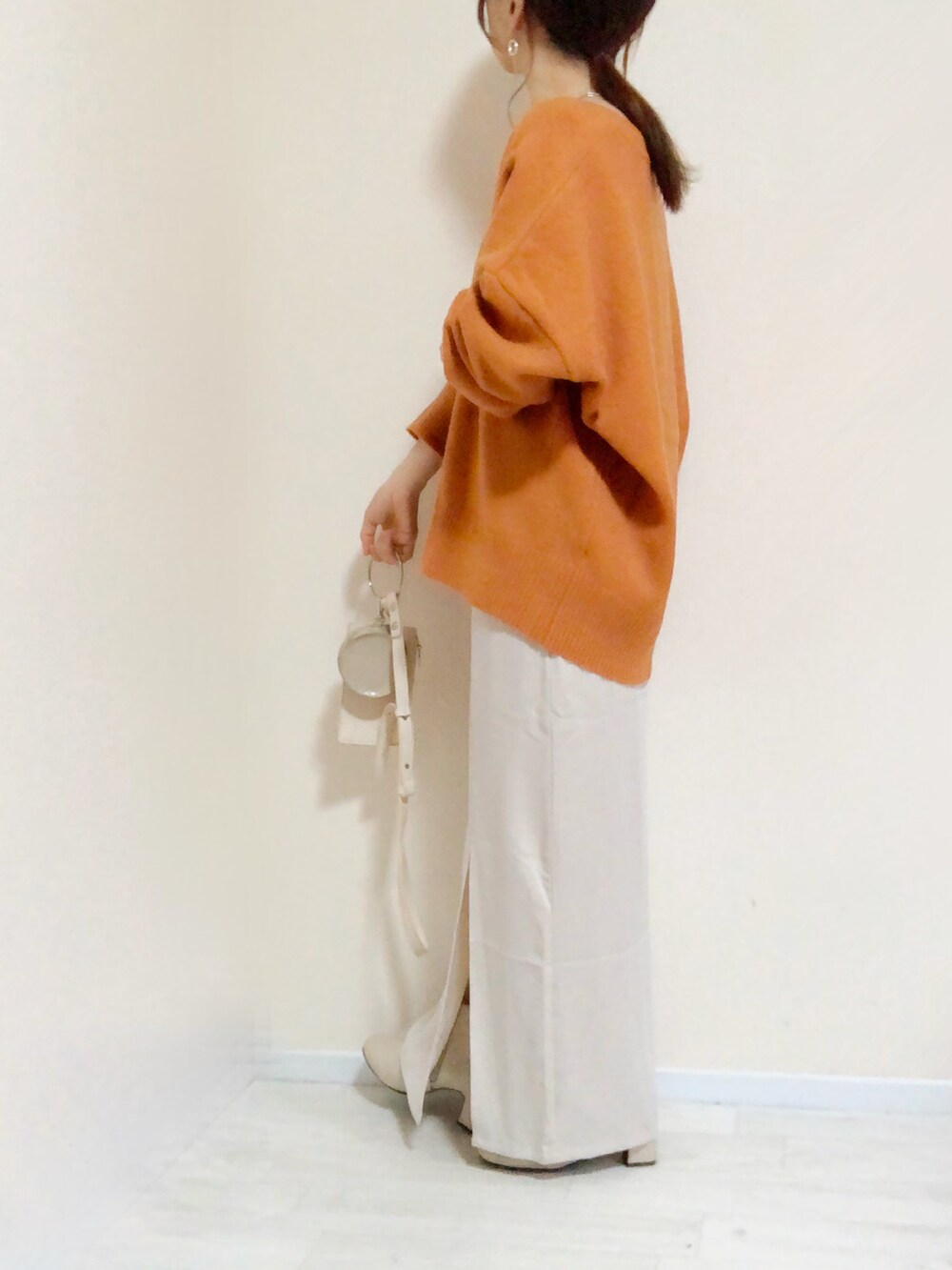 オレンジ系のニット/セーター、ホワイト系のワンピース、ホワイト系のショルダーバッグを着用したレディースの秋コーディネートの2枚目の写真