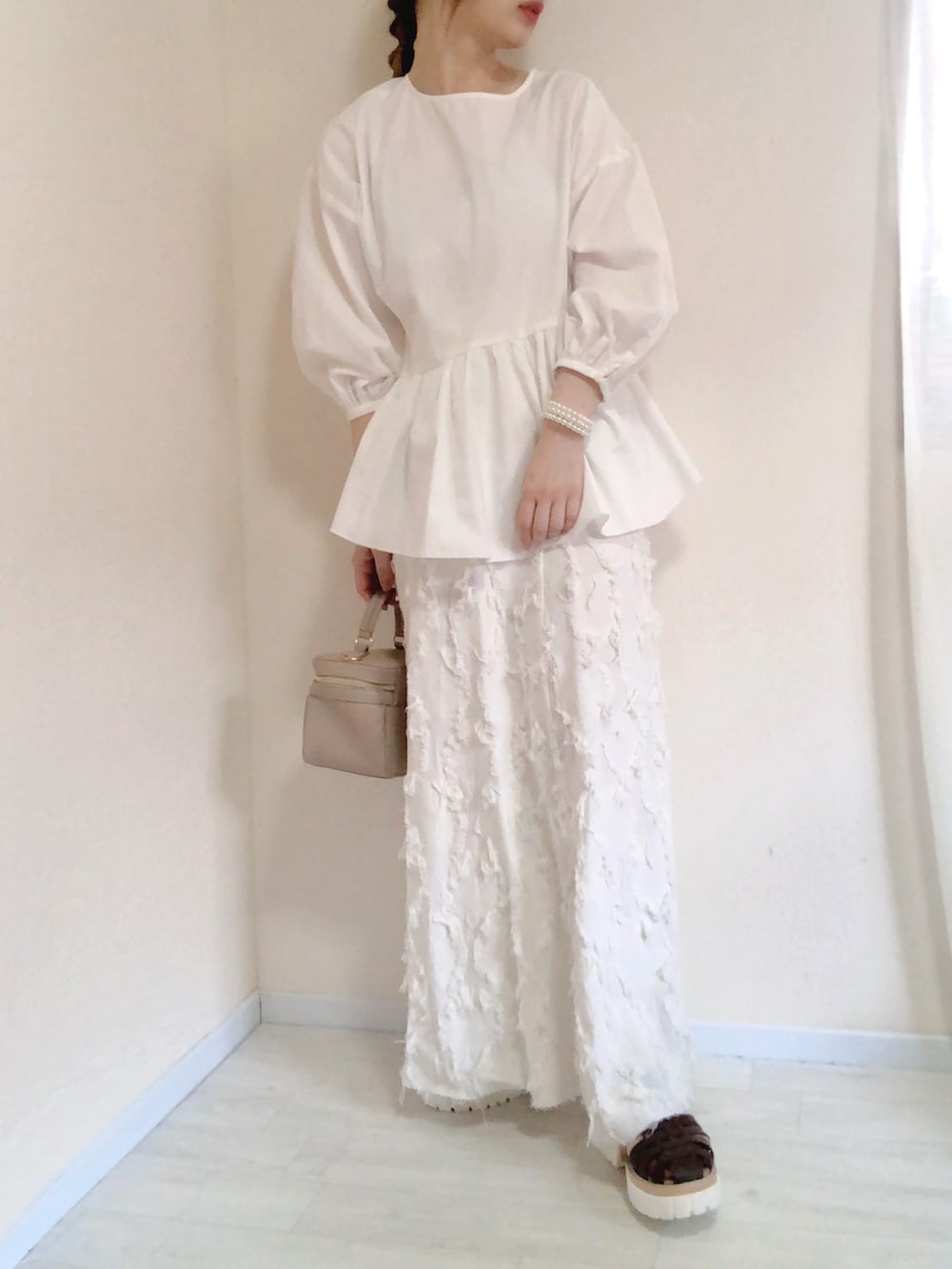 ホワイト系のシャツ/ブラウス、ホワイト系のスカート、ブラウン系のサンダルを着用したレディースの夏コーディネートの2枚目の写真