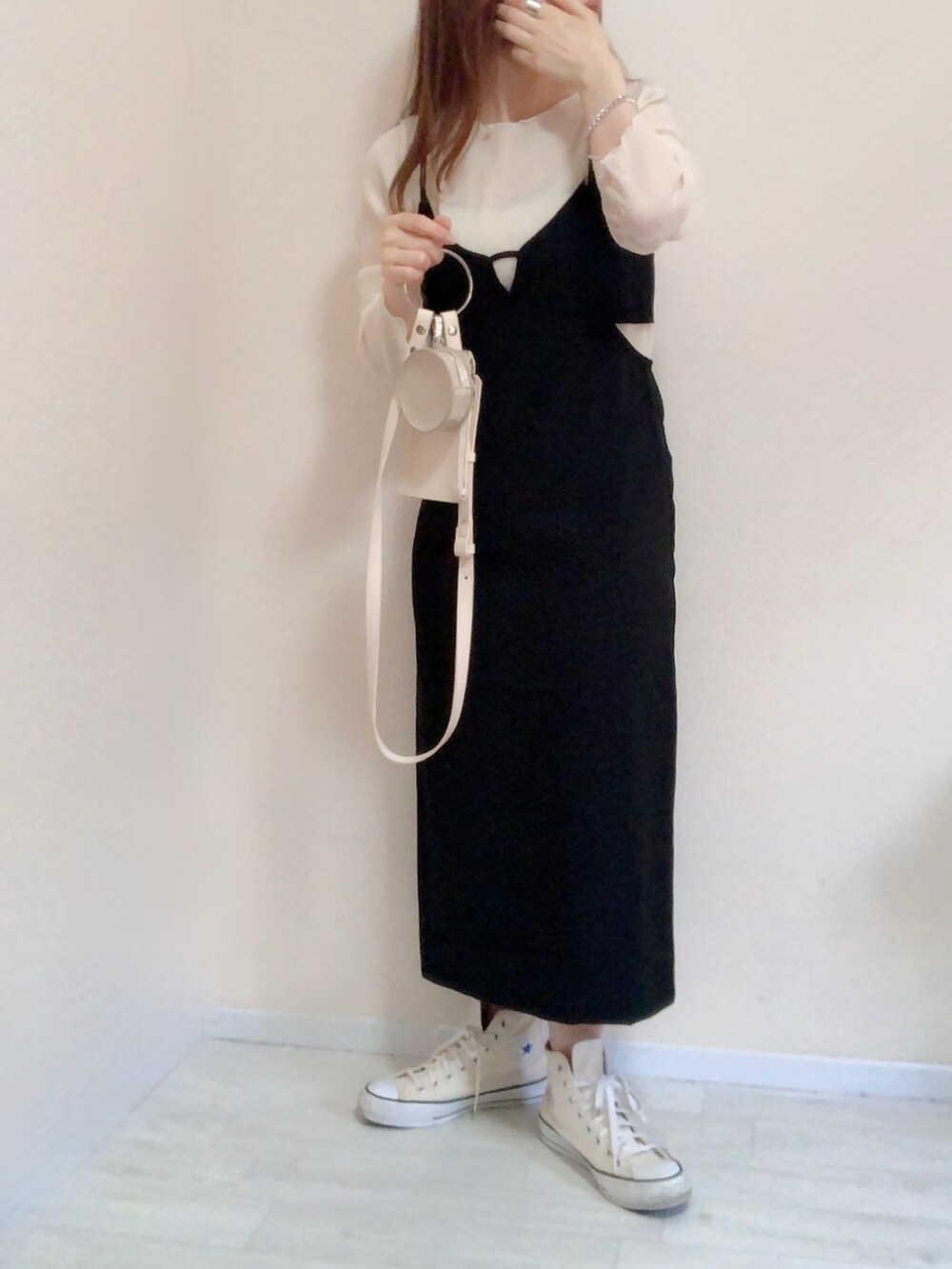 ブラック系のジャンパースカート、ホワイト系のショルダーバッグ、ホワイト系のスニーカーを着用したレディースの春コーディネートの3枚目の写真