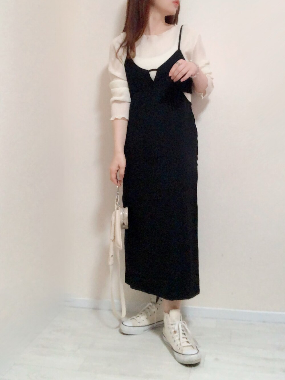 ブラック系のジャンパースカート、ホワイト系のショルダーバッグ、ホワイト系のスニーカーを着用したレディースの春コーディネートの2枚目の写真