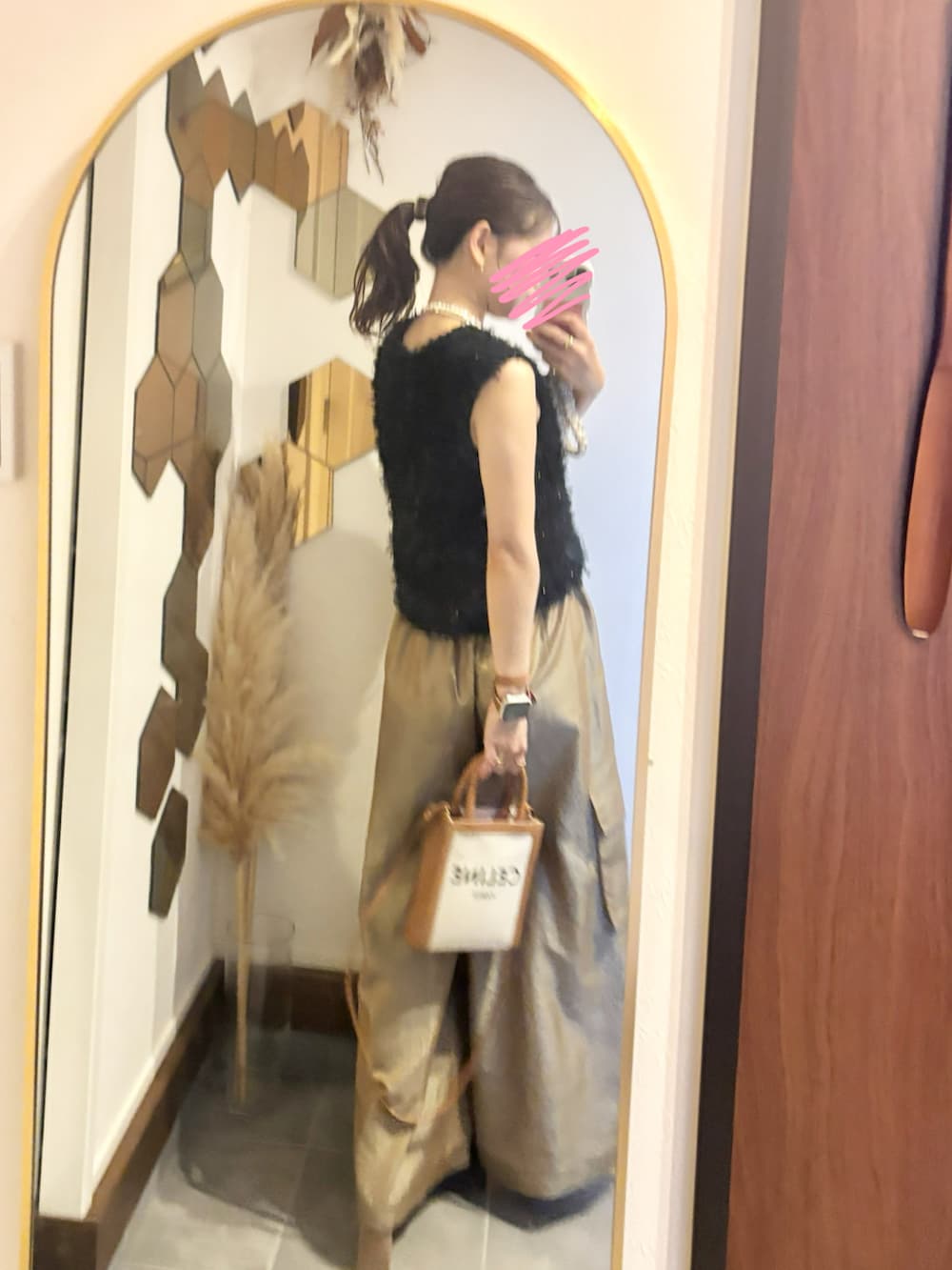 ブラック系のベスト、ゴールド系のカーゴパンツ、ゴールド系のパンプスを着用したレディースの秋コーディネートの2枚目の写真