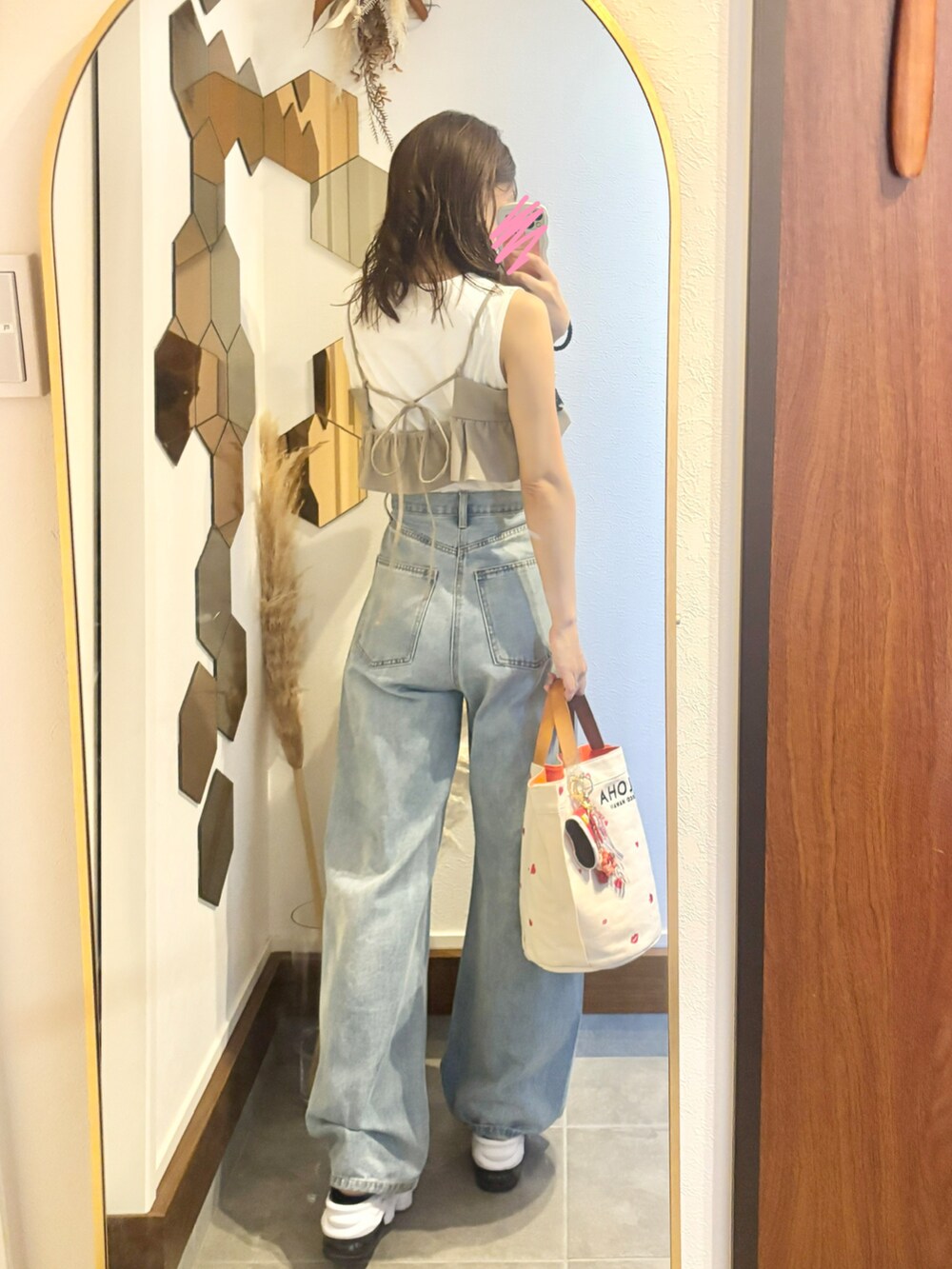 ブルー系のデニムパンツ、ベージュ系のドレス、ホワイト系のトートバッグを着用したレディースの夏コーディネートの2枚目の写真