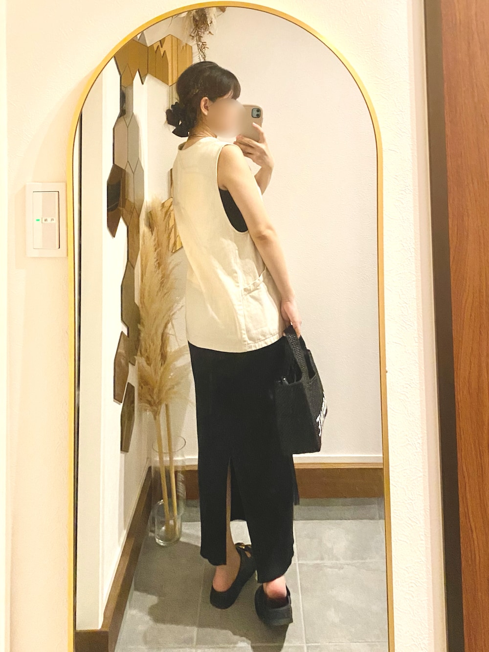 ブラック系のスカート、ホワイト系のベスト、ブラック系のトートバッグを着用したレディースの夏コーディネートの2枚目の写真