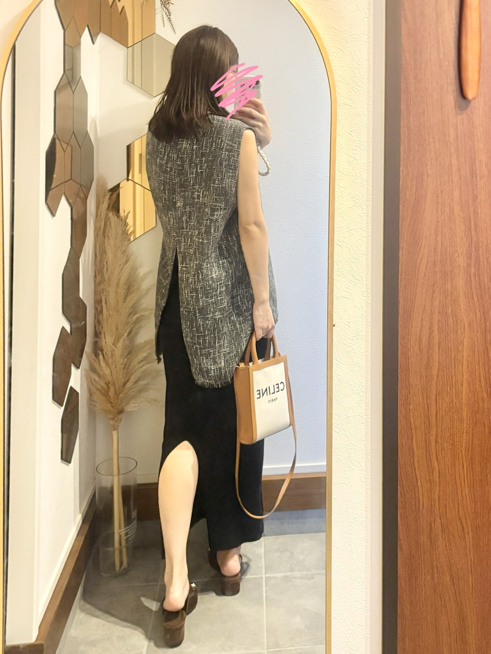 グレー系のベスト、ブラック系のワンピース、ベージュ系のショルダーバッグを着用したレディースの夏コーディネートの2枚目の写真