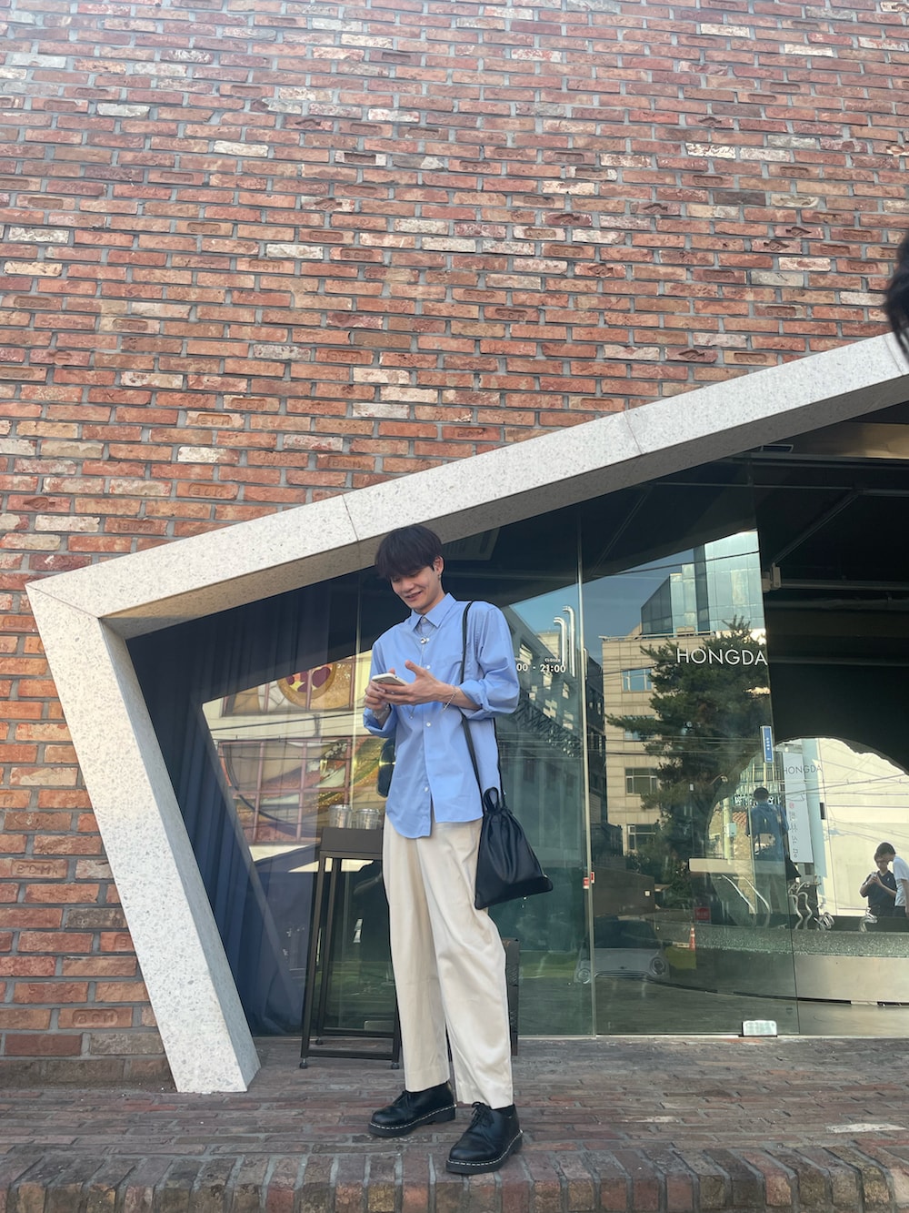 ブルー系のシャツ/ブラウス、ブラック系のショルダーバッグ、ホワイト系のスラックスを着用したメンズの夏コーディネートの5枚目の写真