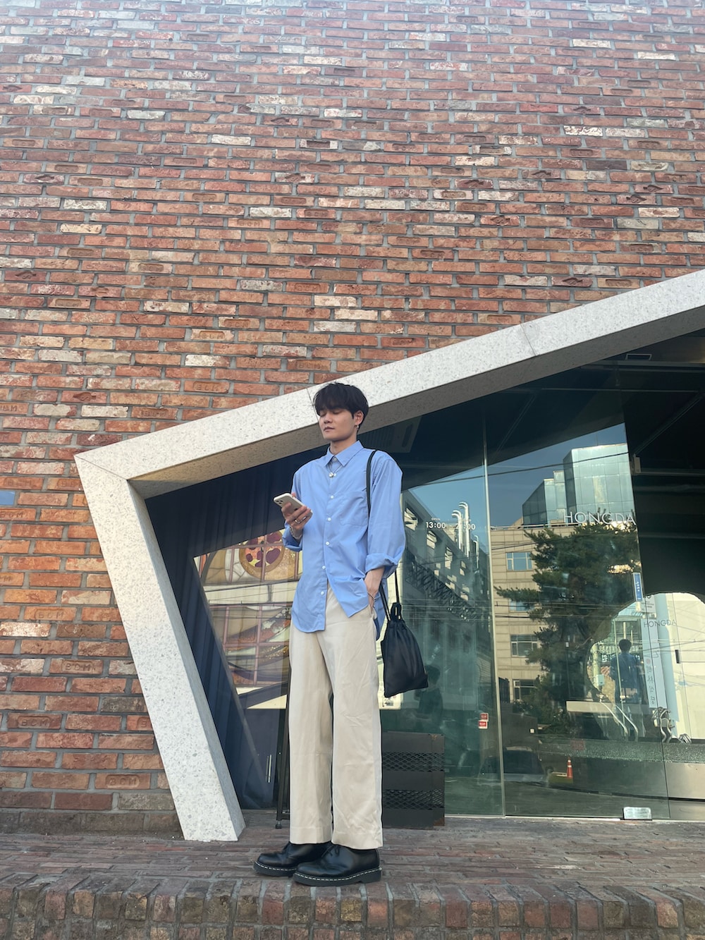 ブルー系のシャツ/ブラウス、ブラック系のショルダーバッグ、ホワイト系のスラックスを着用したメンズの夏コーディネートの2枚目の写真