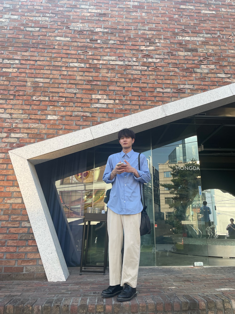 ブルー系のシャツ/ブラウス、ブラック系のショルダーバッグ、ホワイト系のスラックスを着用したメンズの夏コーディネートの4枚目の写真