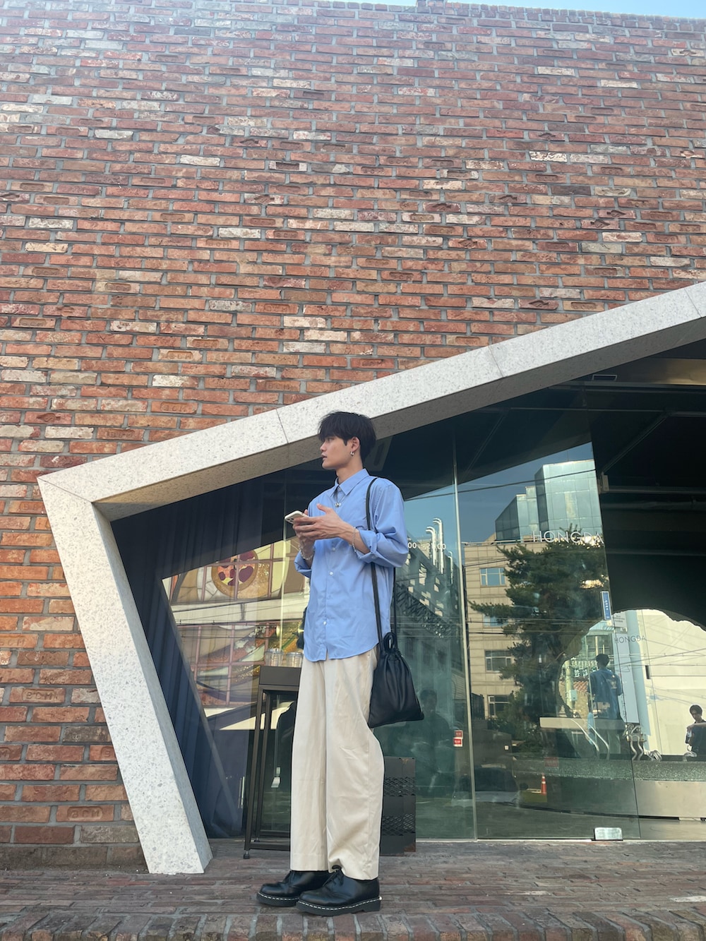 ブルー系のシャツ/ブラウス、ブラック系のショルダーバッグ、ホワイト系のスラックスを着用したメンズの夏コーディネートの3枚目の写真