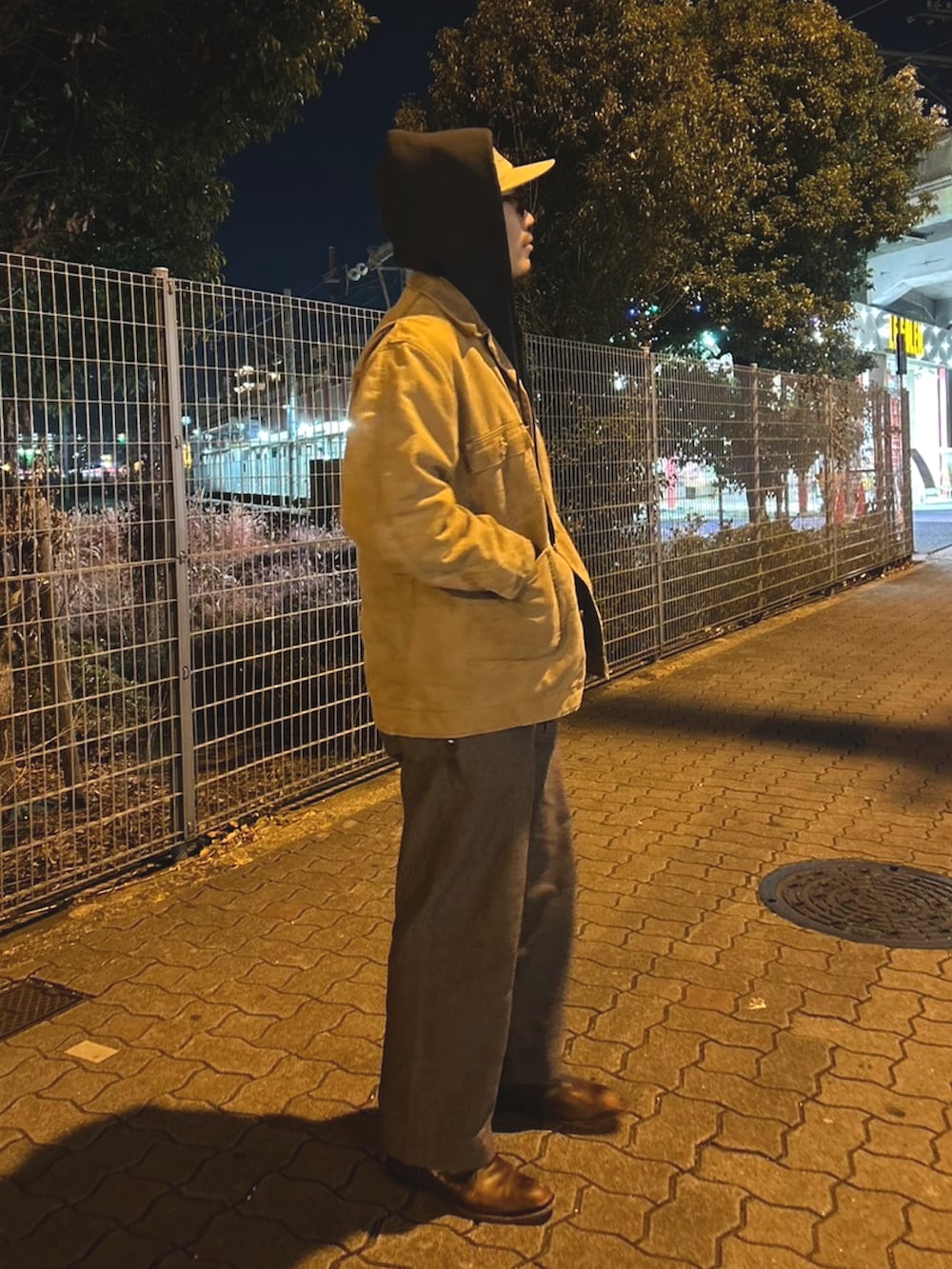 グレー系のパンツ、ベージュ系のカバーオール、ブラック系のパーカーを着用したメンズの秋コーディネートの2枚目の写真