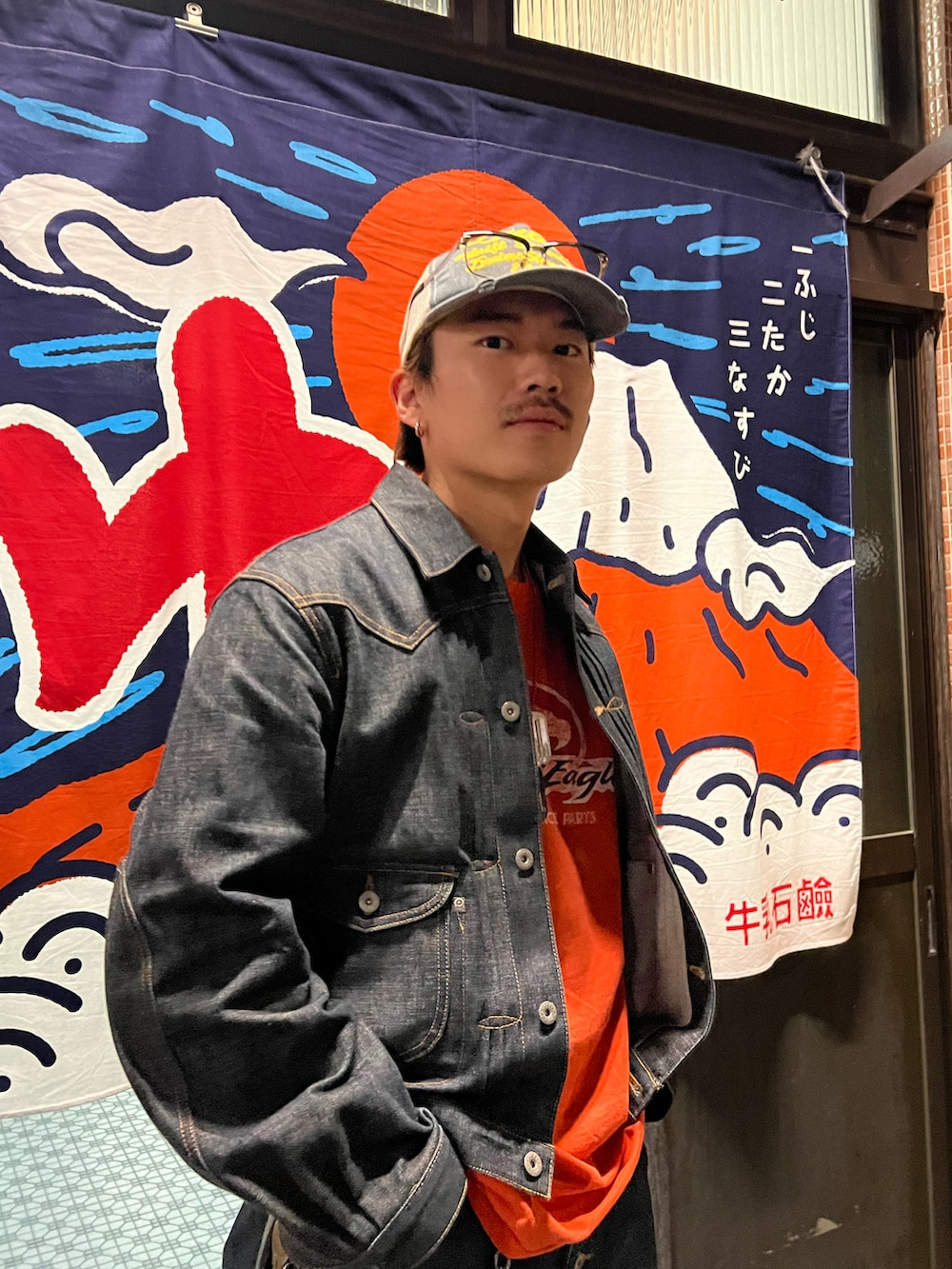 ブルー系のデニムジャケット、ブルー系のデニムパンツ、ホワイト系のスニーカーを着用したメンズの秋コーディネートの2枚目の写真