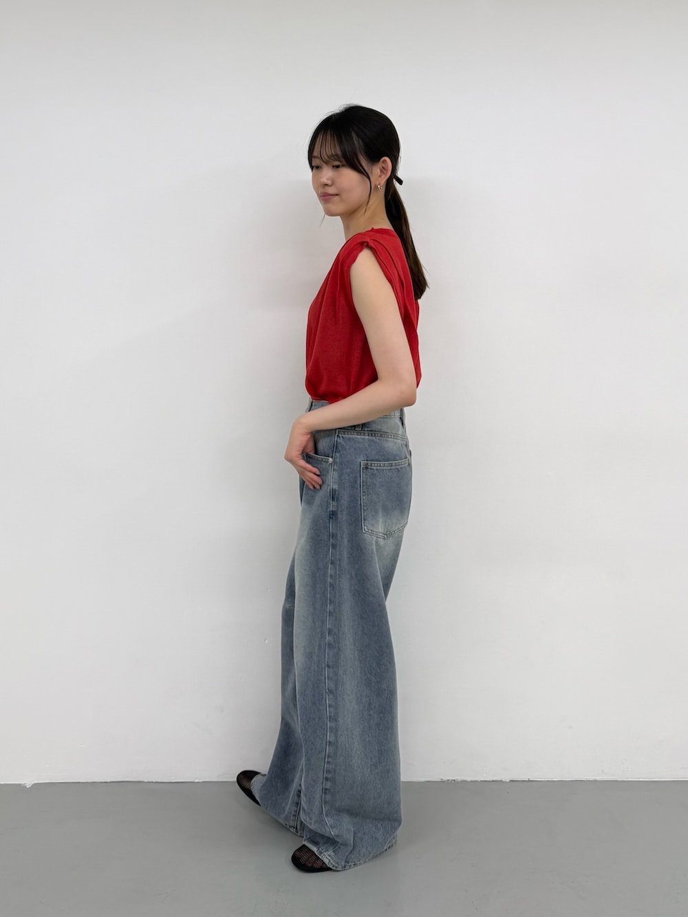 レッド系のニット/セーター、ブルー系のデニムパンツ、ブルー系のデニムパンツを着用したレディースの夏コーディネートの2枚目の写真