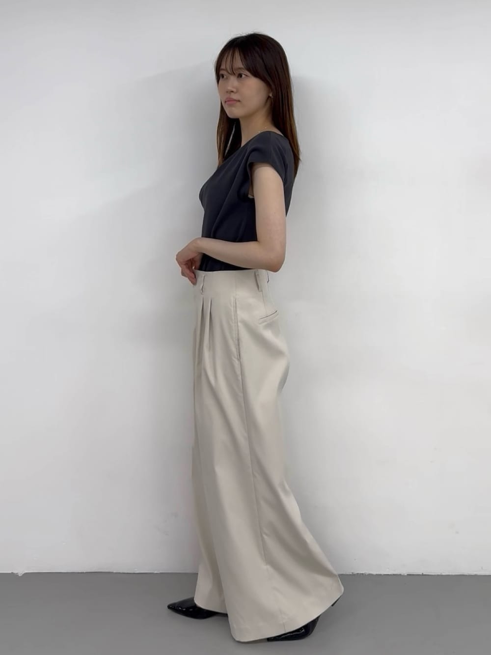 グレー系のニット/セーター、ホワイト系のチノパンツ、ホワイト系のチノパンツを着用したレディースの夏コーディネートの2枚目の写真