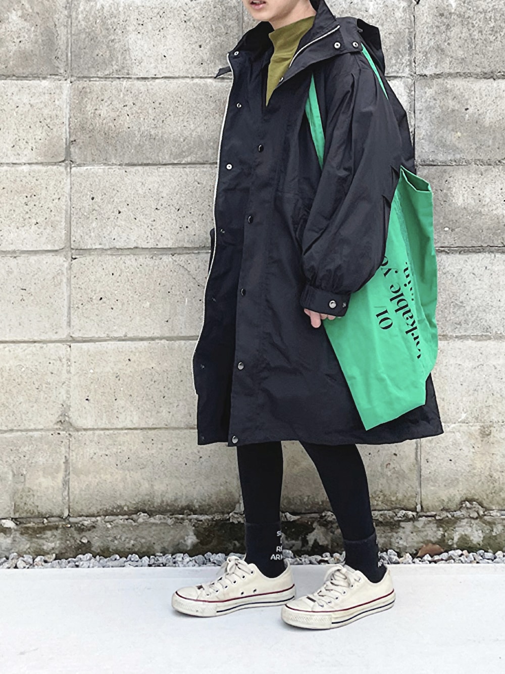 ブラック系のモッズコート、グリーン系のTシャツ/カットソー、グリーン系のエコバッグ/サブバッグを着用したキッズの冬コーディネートの3枚目の写真