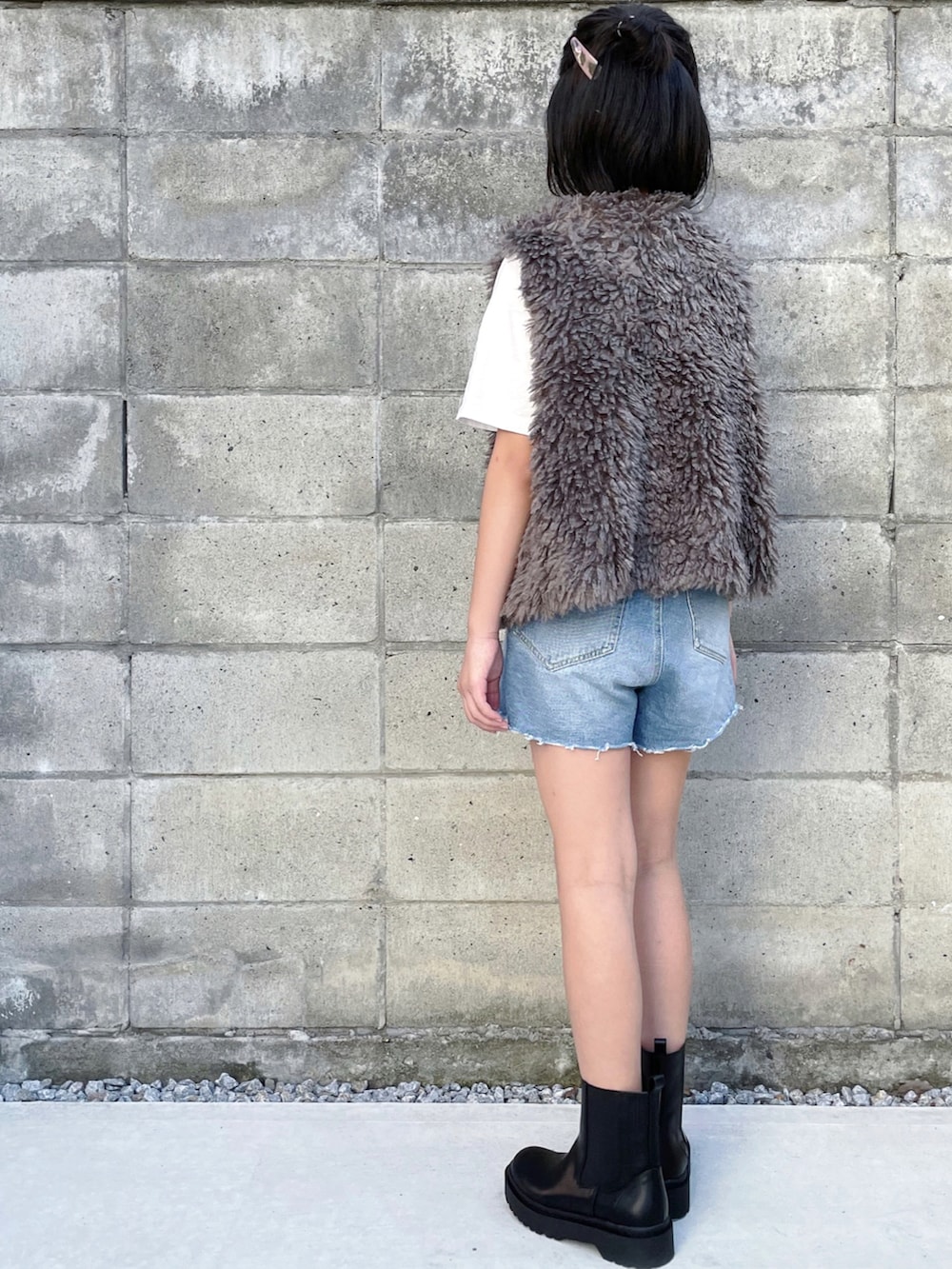 ブラウン系のベスト、ブルー系のデニムパンツ、ブラック系のブーツを着用したキッズの秋コーディネートの2枚目の写真