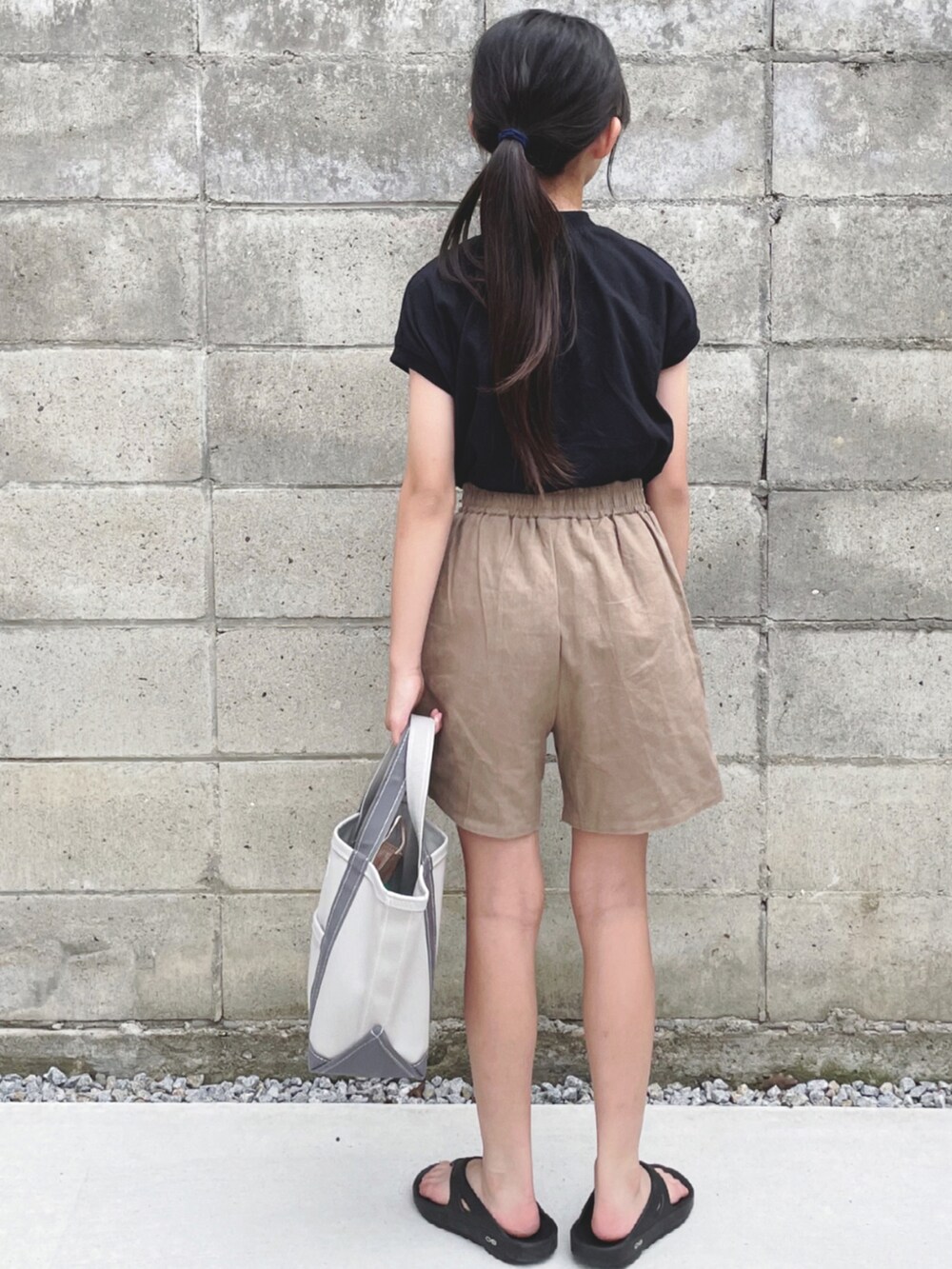 グレー系のトートバッグ、ブラック系のTシャツ/カットソー、ブラウン系のセットアップを着用したキッズの夏コーディネートの2枚目の写真