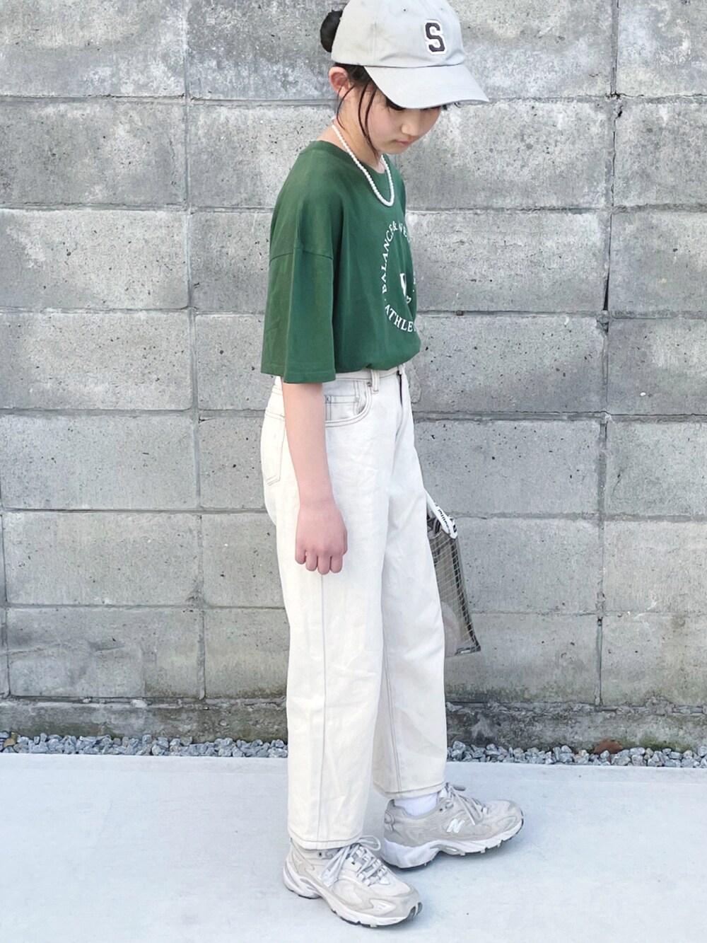 ベージュ系のデニムパンツ、ブラック系のショルダーバッグ、ベージュ系のスニーカーを着用したキッズの春コーディネートの2枚目の写真