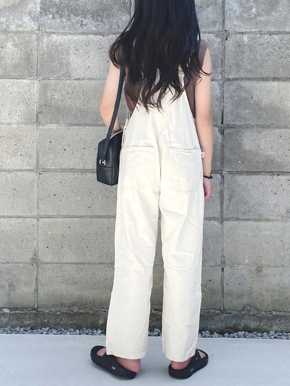 ブラック系のショルダーバッグ、ホワイト系のサロペット/オーバーオール、ブラウン系のタンクトップを着用したキッズの夏コーディネートの2枚目の写真