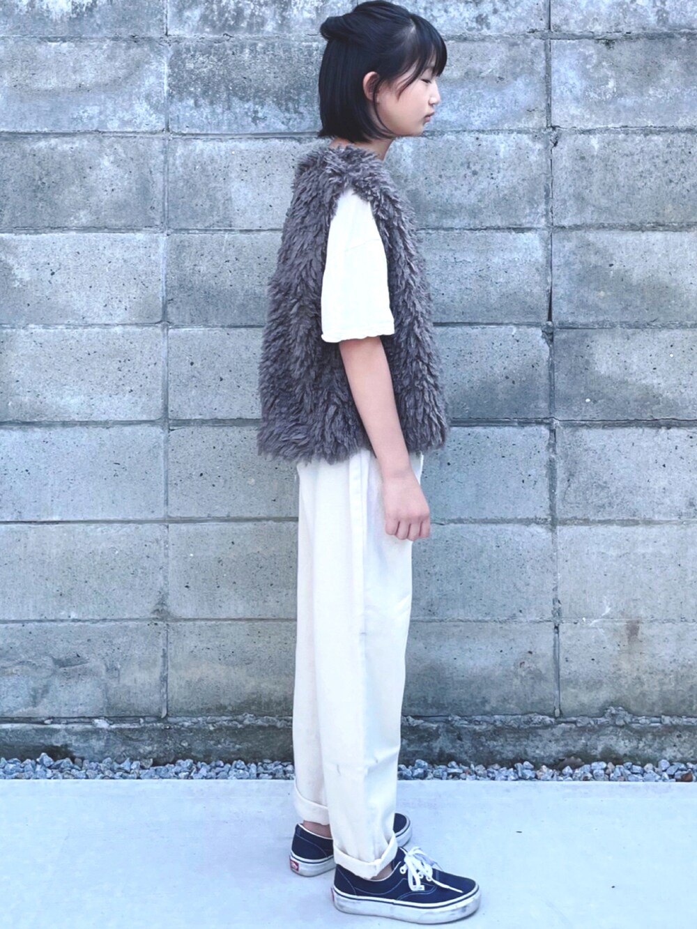 ブルー系のスニーカー、ブラウン系のベスト、ホワイト系のデニムパンツを着用したキッズの秋コーディネートの2枚目の写真