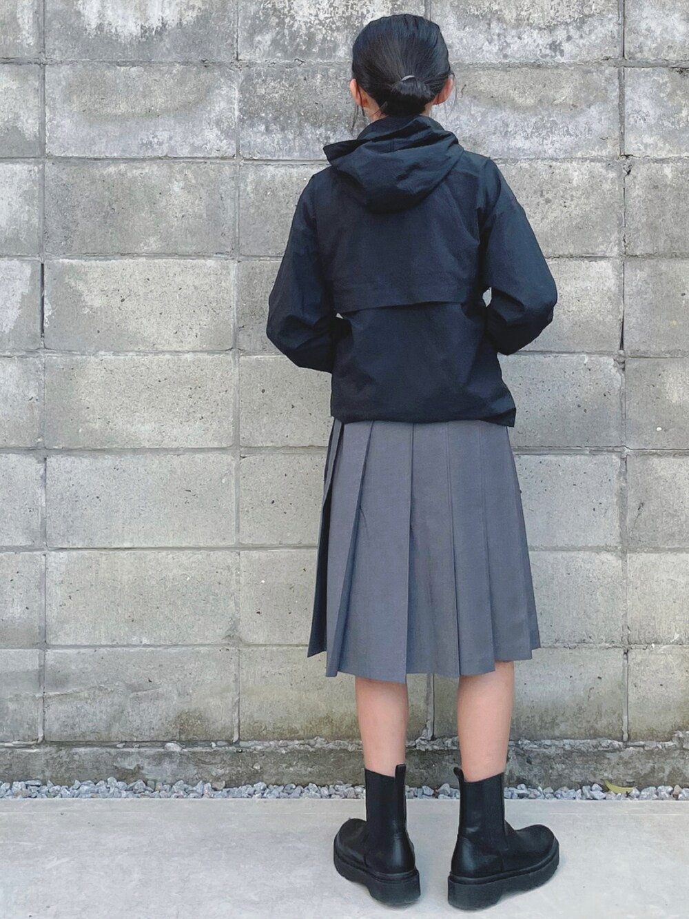 グレー系のスカート、ブラック系のブーツ、ブラック系のナイロンジャケットを着用したキッズの秋コーディネートの2枚目の写真